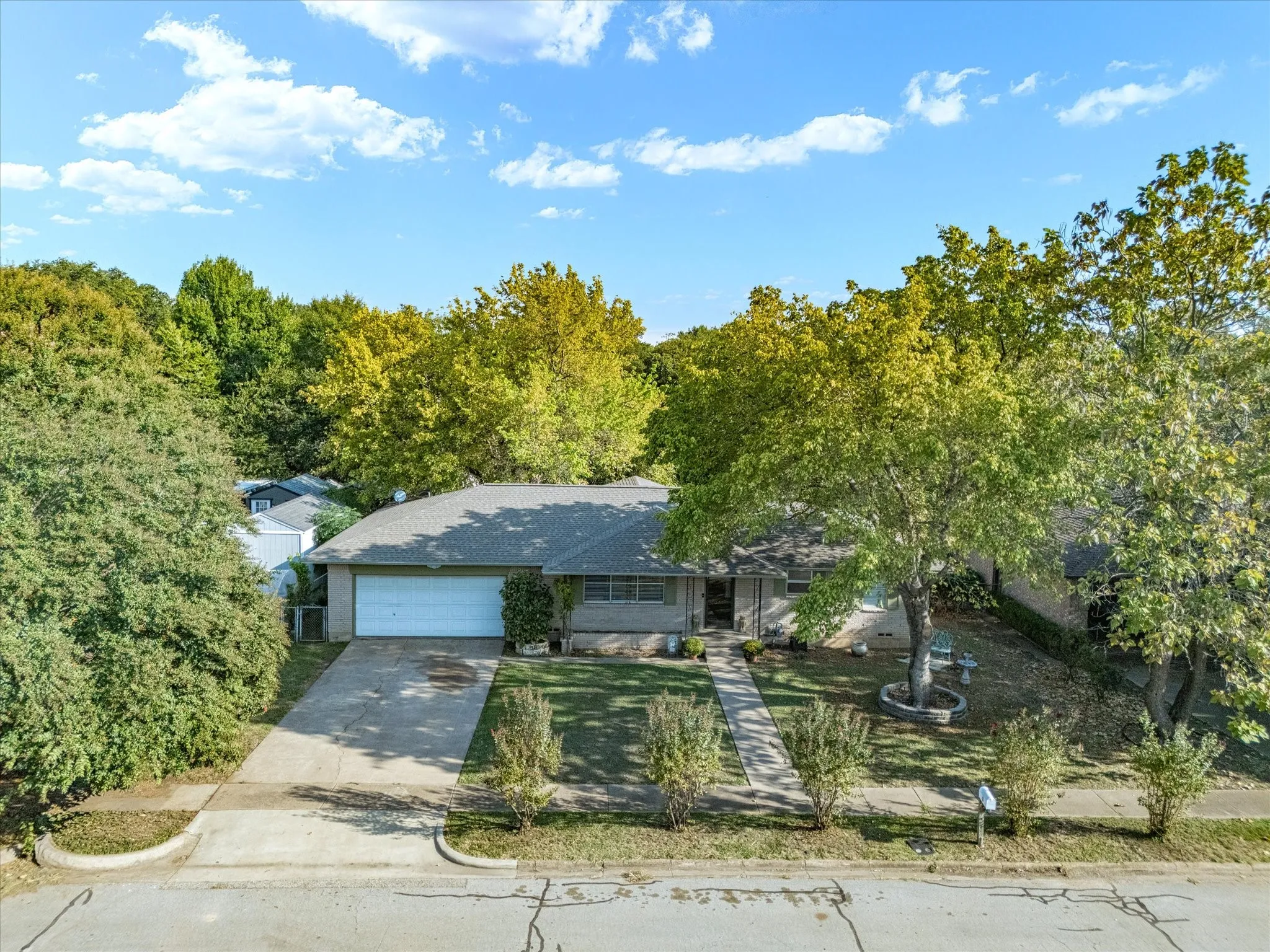 Single-story residence featuring a gray shingle roof, attached garage, and a concrete driveway