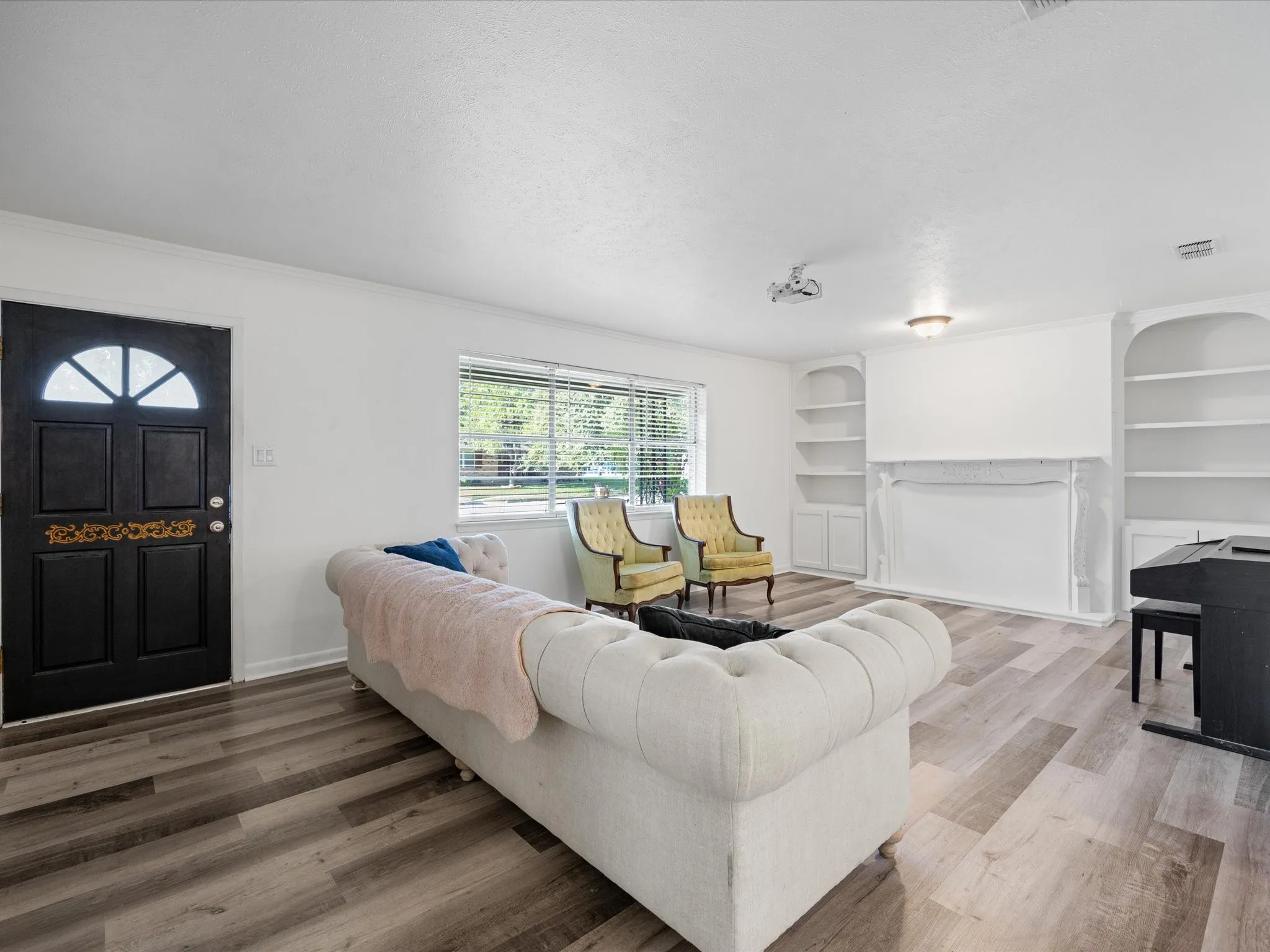Wood-finish flooring, built-in shelving, white walls, and a front entry door with an arched transom