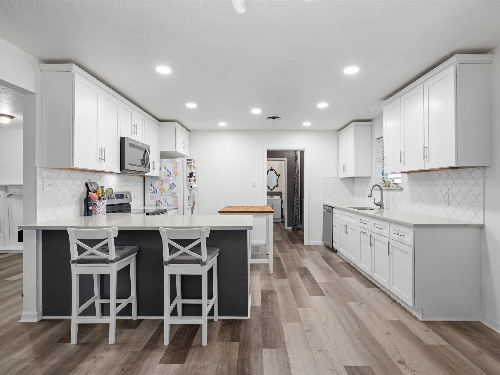 Kitchen featuring wood-finish flooring, white cabinetry, a built-in microwave, and a stainless steel dishwasher
