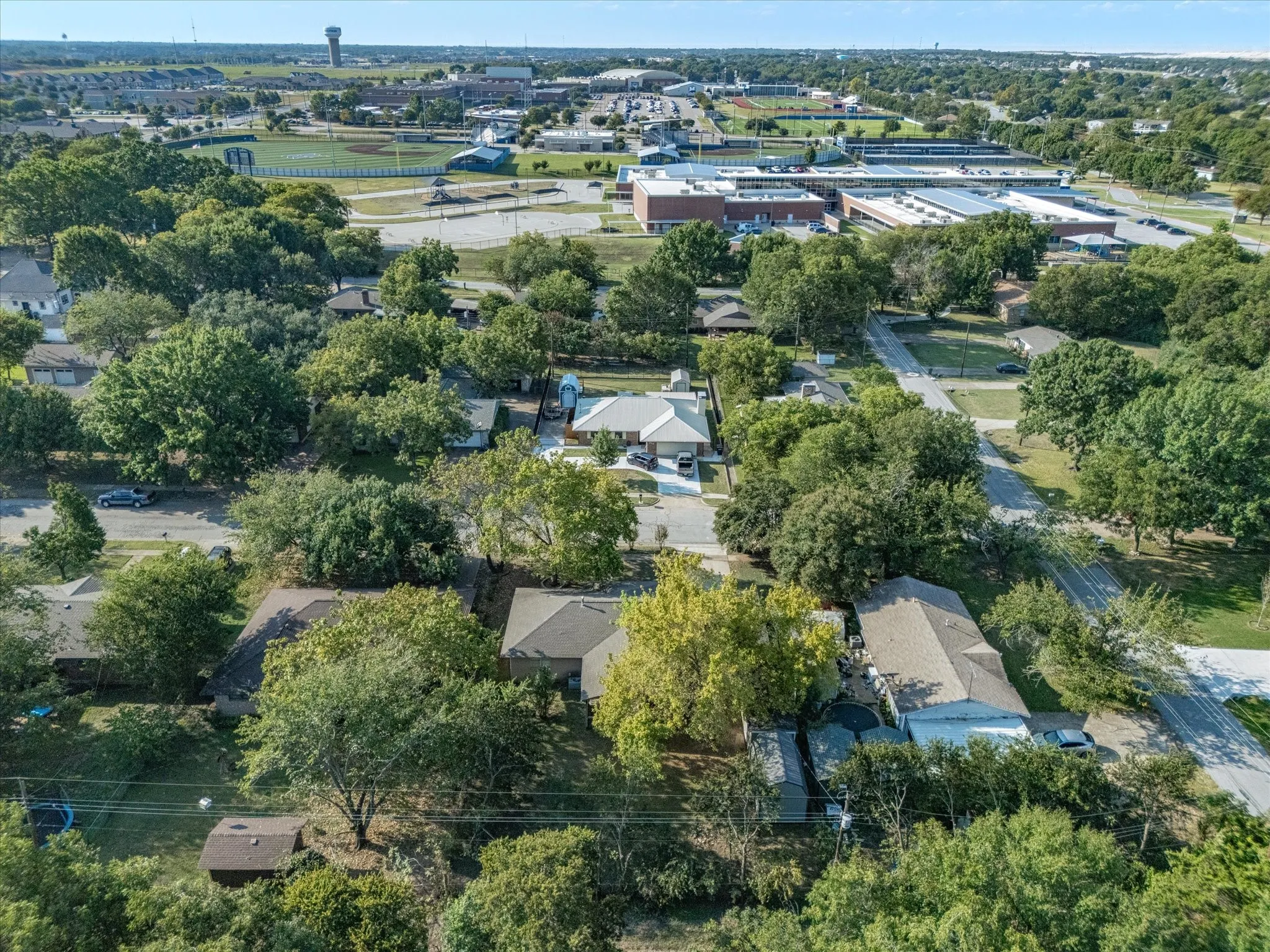 Aerial perspective showcasing residential properties with mature trees and paved roadways