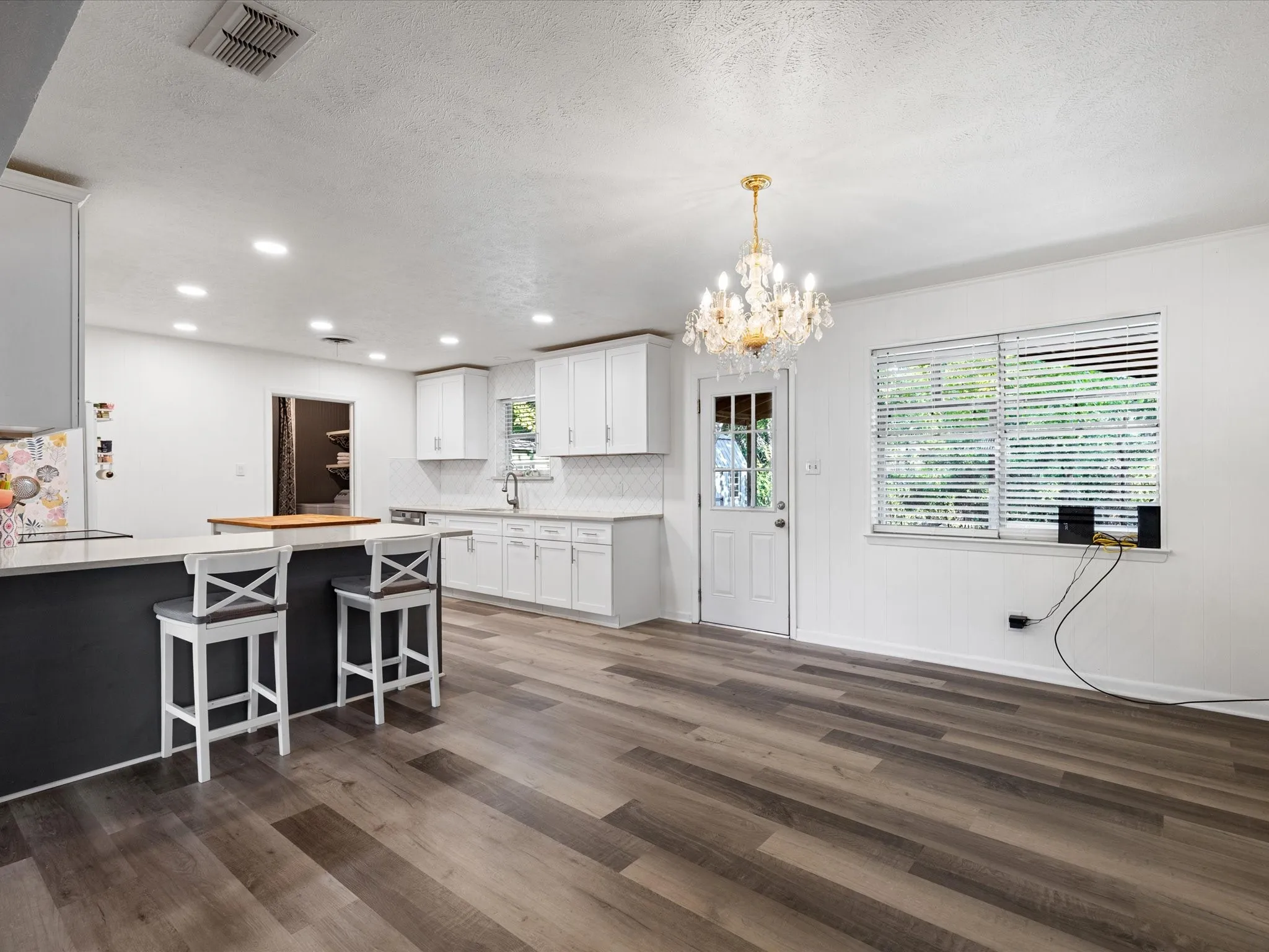 Kitchen featuring white cabinetry, a large kitchen island, wood-finish flooring, recessed lighting, and a crystal chandelier