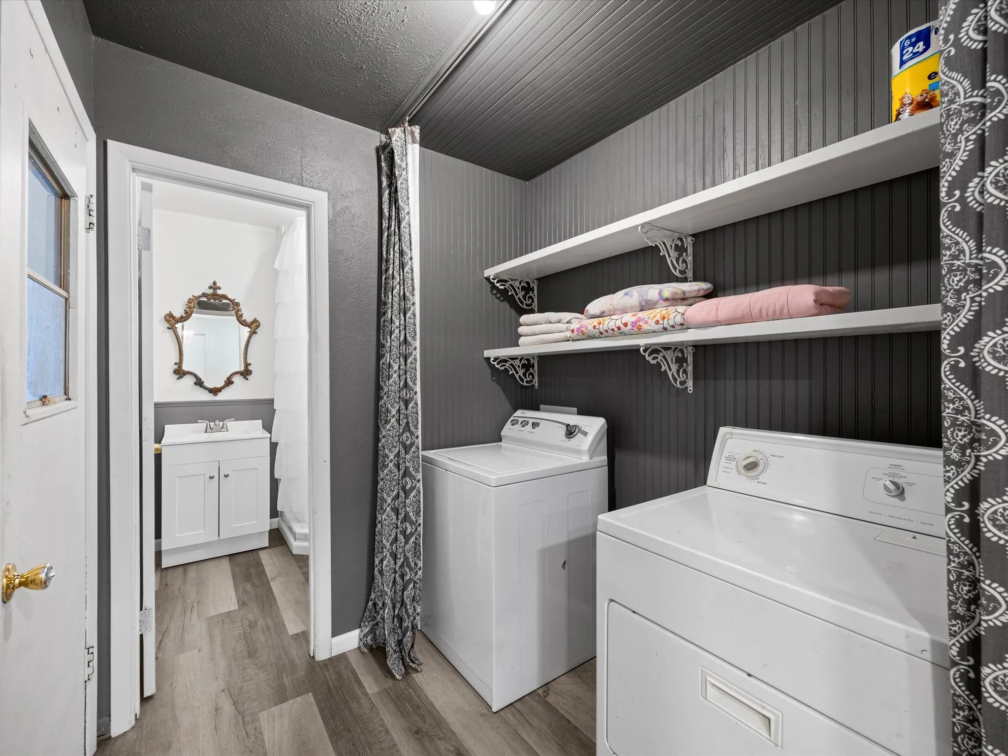 Laundry area with wood-finish flooring, beadboard wall paneling, and built-in shelving