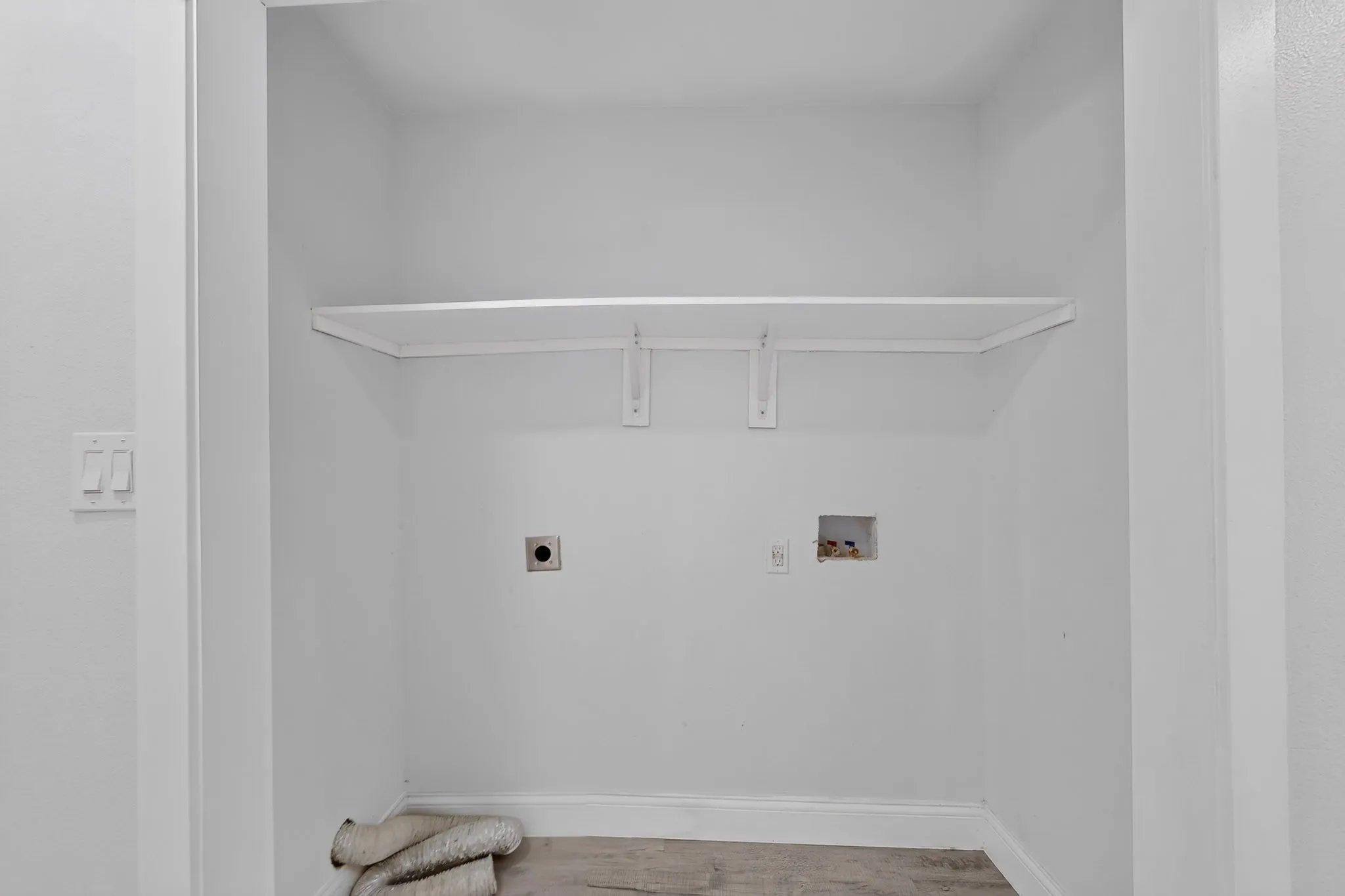 Dedicated laundry area with a built-in shelf, plumbing hookups, and electrical outlets