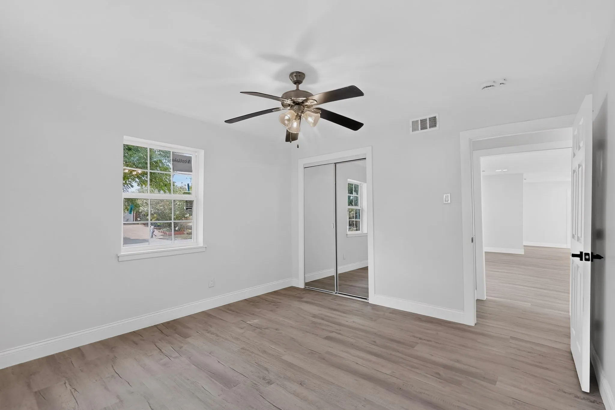 Wood-finish flooring, ceiling fan with integrated lighting, mirrored closet doors, and recessed lighting in the adjacent space