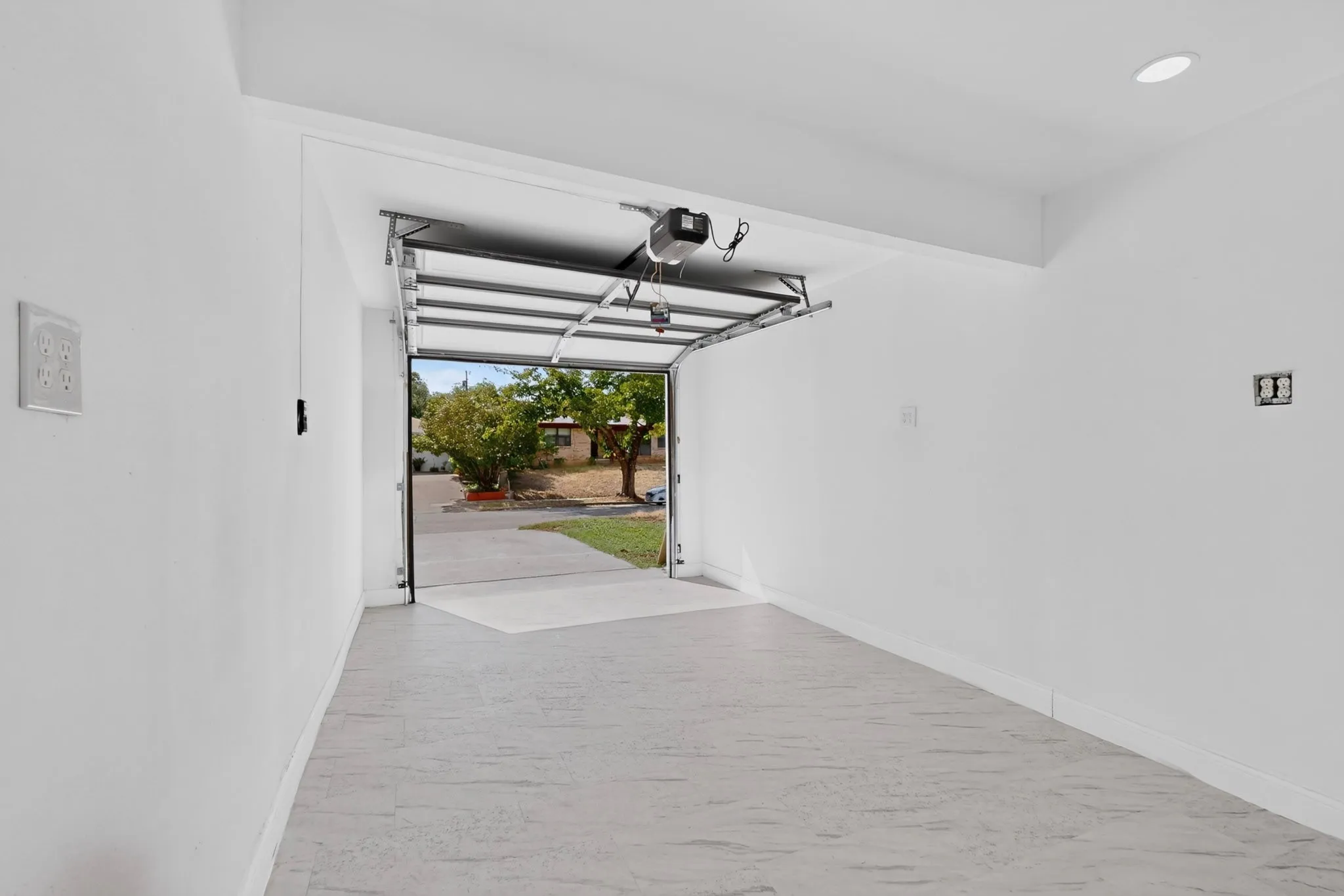 Attached garage featuring an automatic opener, white walls, and a light-toned concrete floor