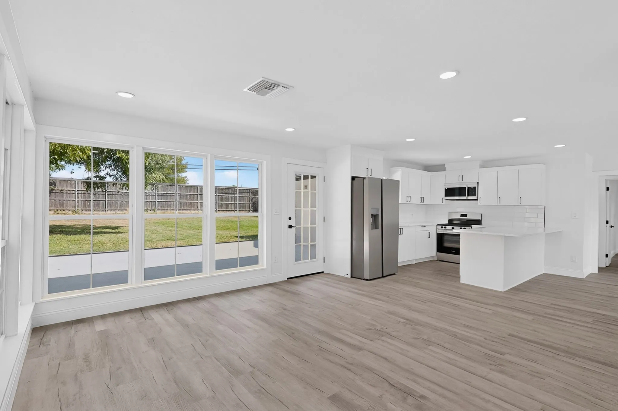 Open-concept living area with wood-finish flooring, recessed lighting, and expansive windows