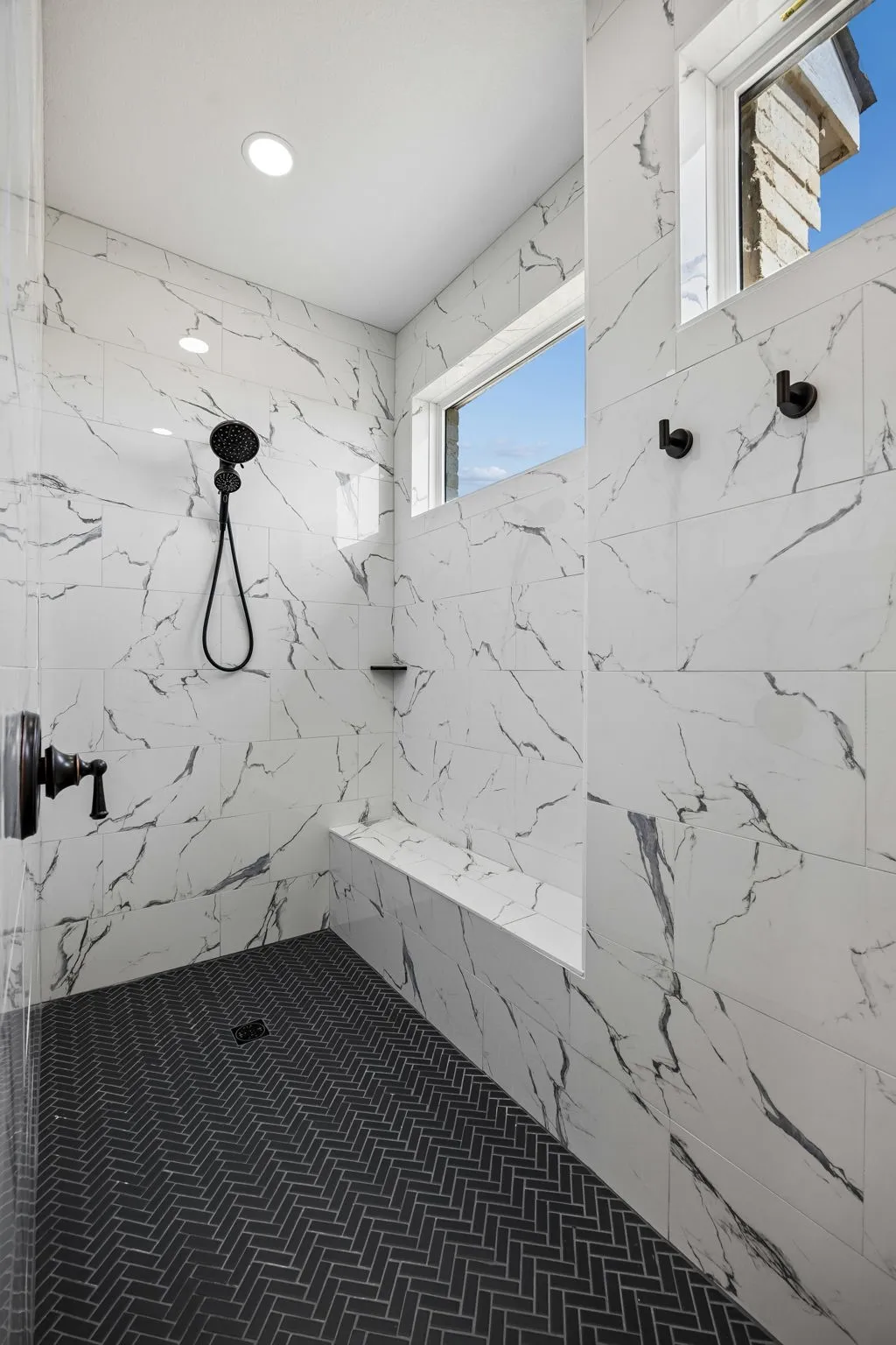 Large luxurious shower with marble and designer tile finishes