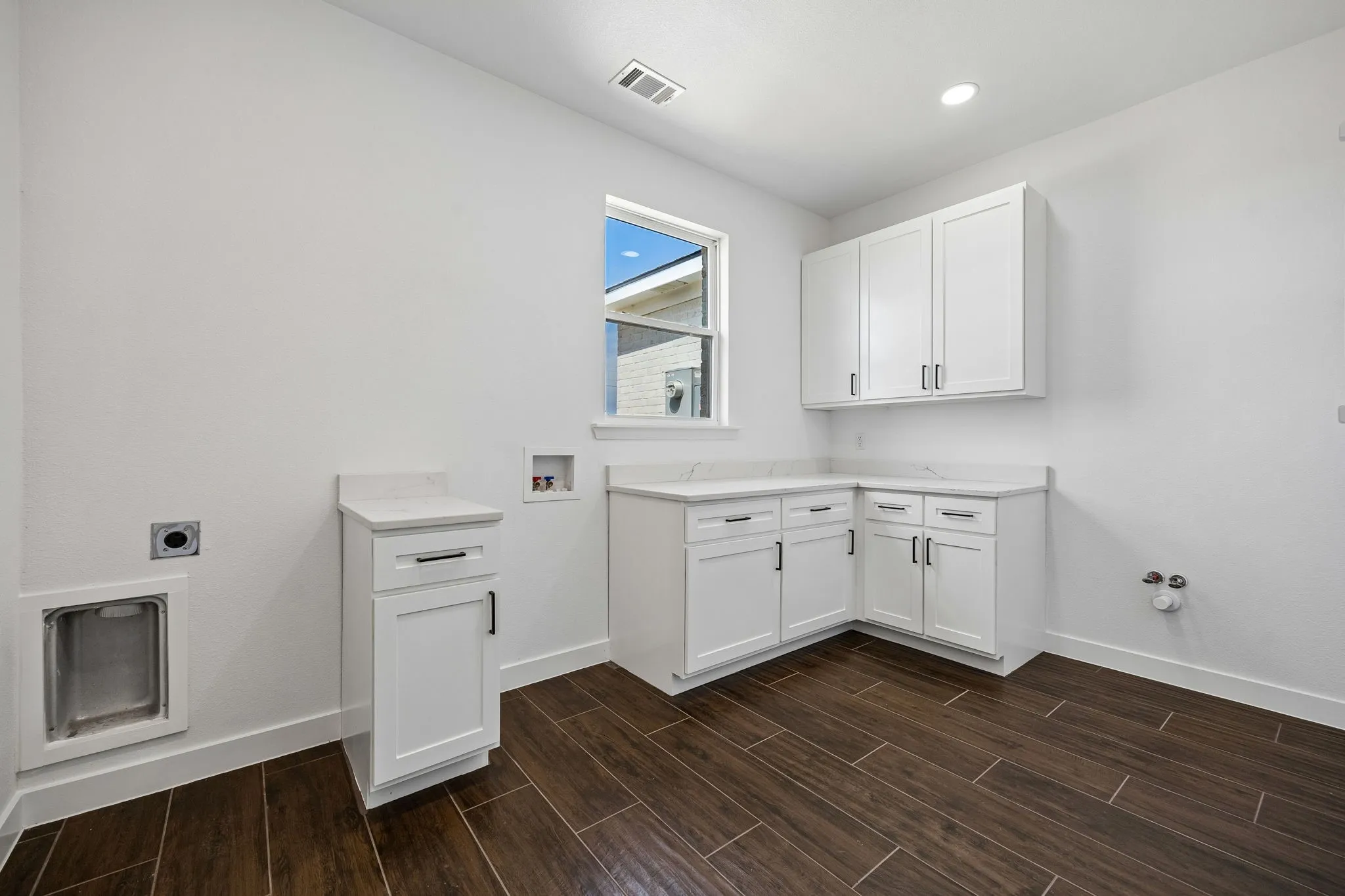Spacious utility room with built-in cabinets and plumbing for sink already installed ready for your customization.