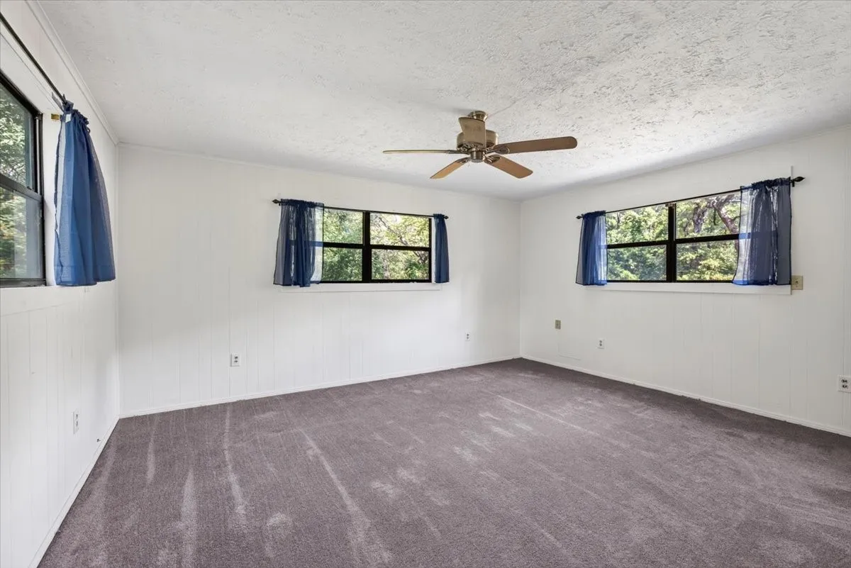 Textured white walls, gray carpeting, and multiple windows