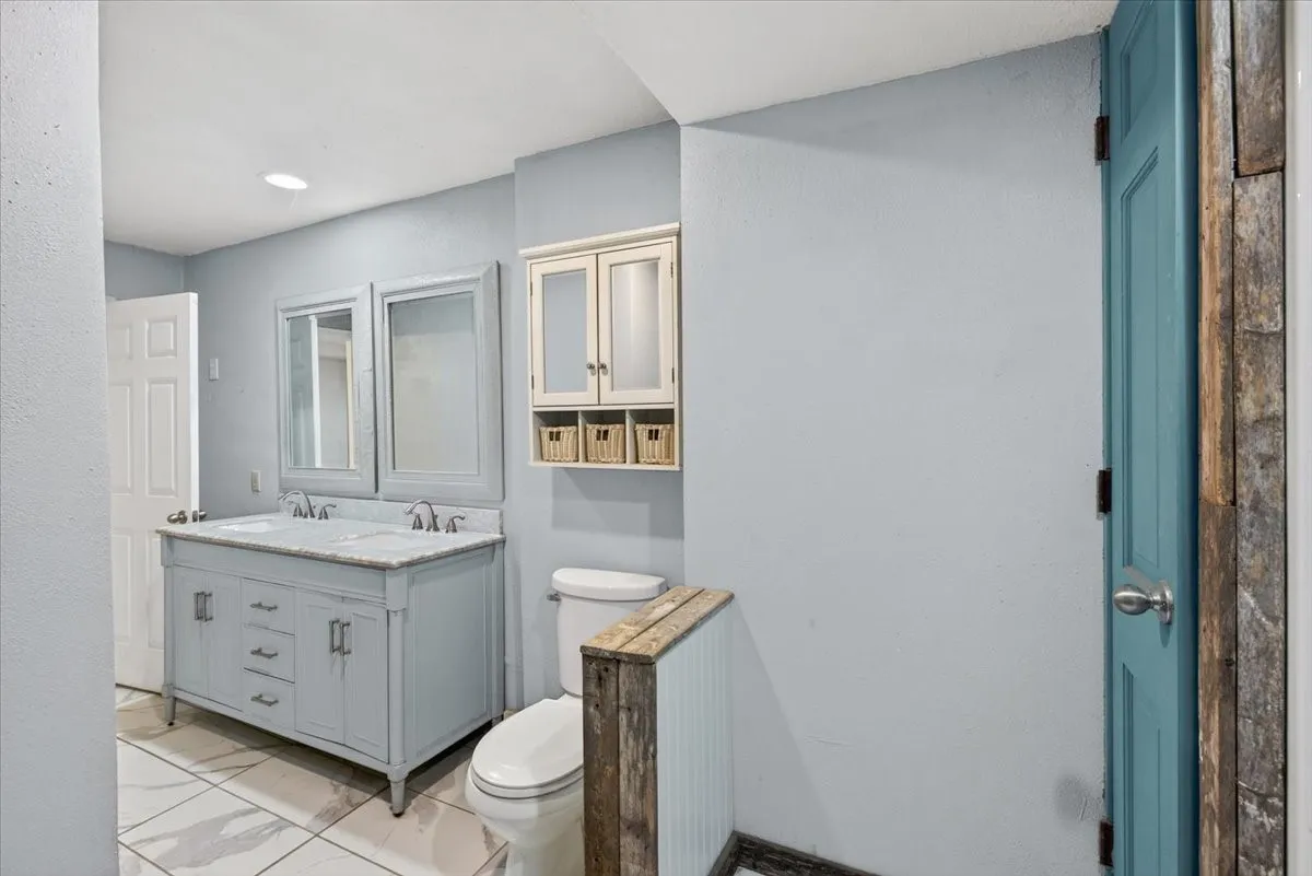 Dual vanity with a stone countertop, individual framed mirrors, recessed ceiling lighting, and tiled flooring