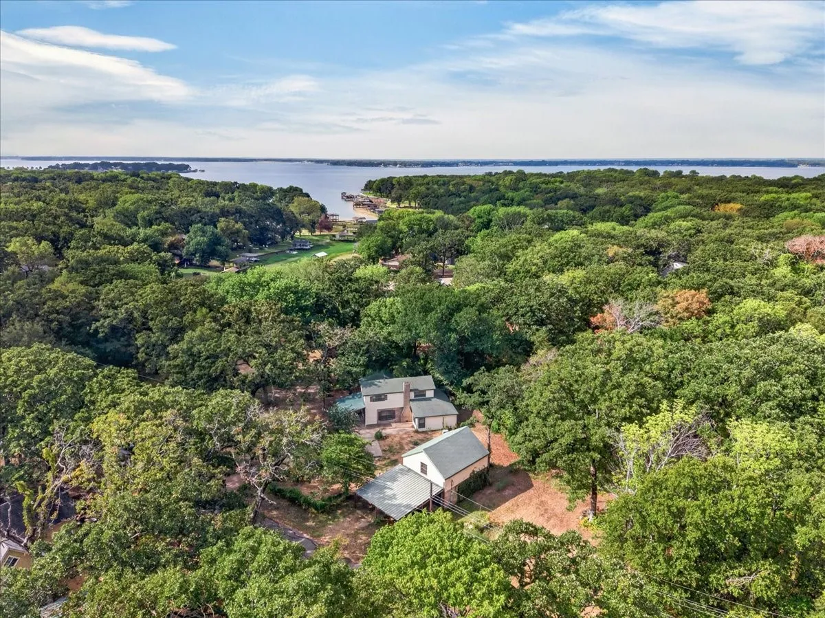 Expansive wooded property with a two-story residence and a separate outbuilding, situated in a tree-canopied setting