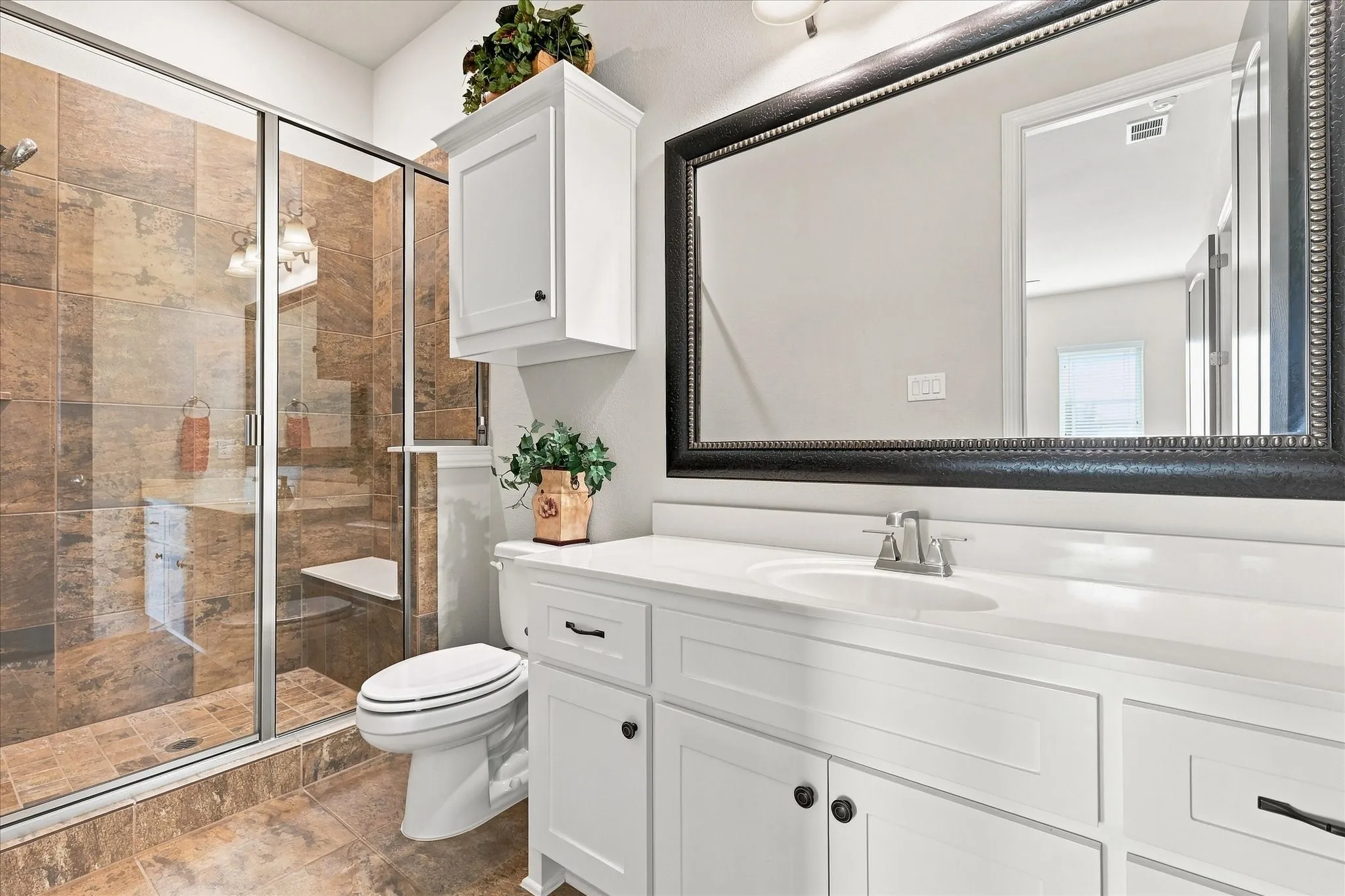 Enclosed shower with a built-in bench, glass door, and large format tile