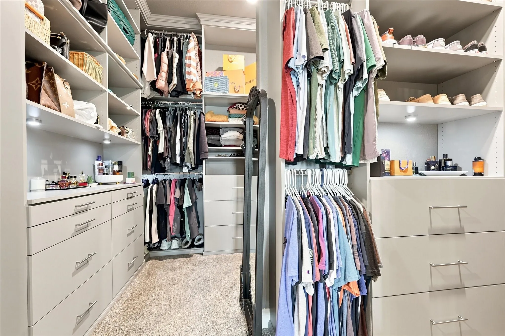 Custom closet system featuring built-in shelving, integrated lighting, multiple hanging rods, and extensive drawer storage