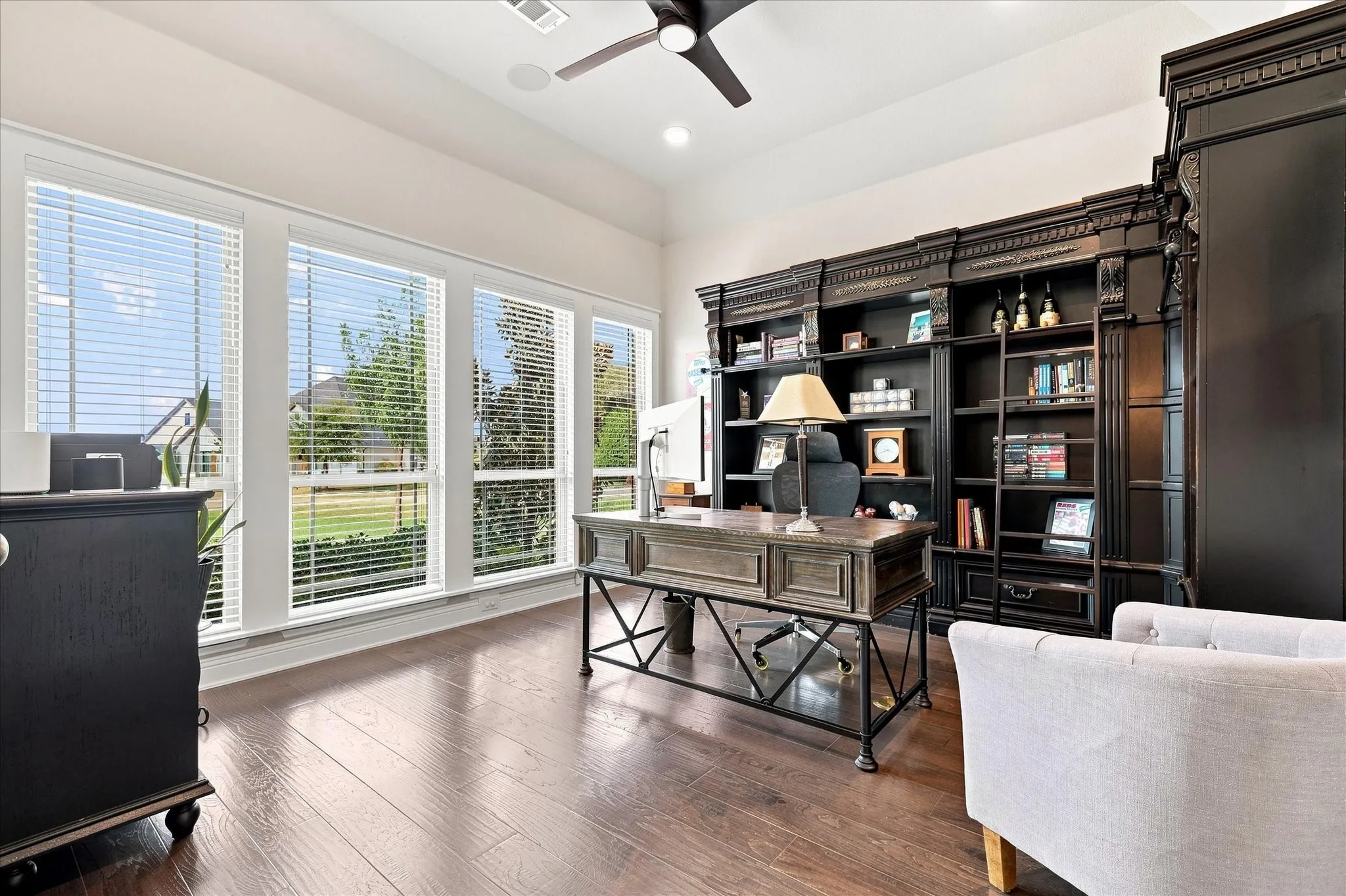 Wood-finish flooring, multiple large windows, a built-in ceiling fan, and extensive built-in shelving
