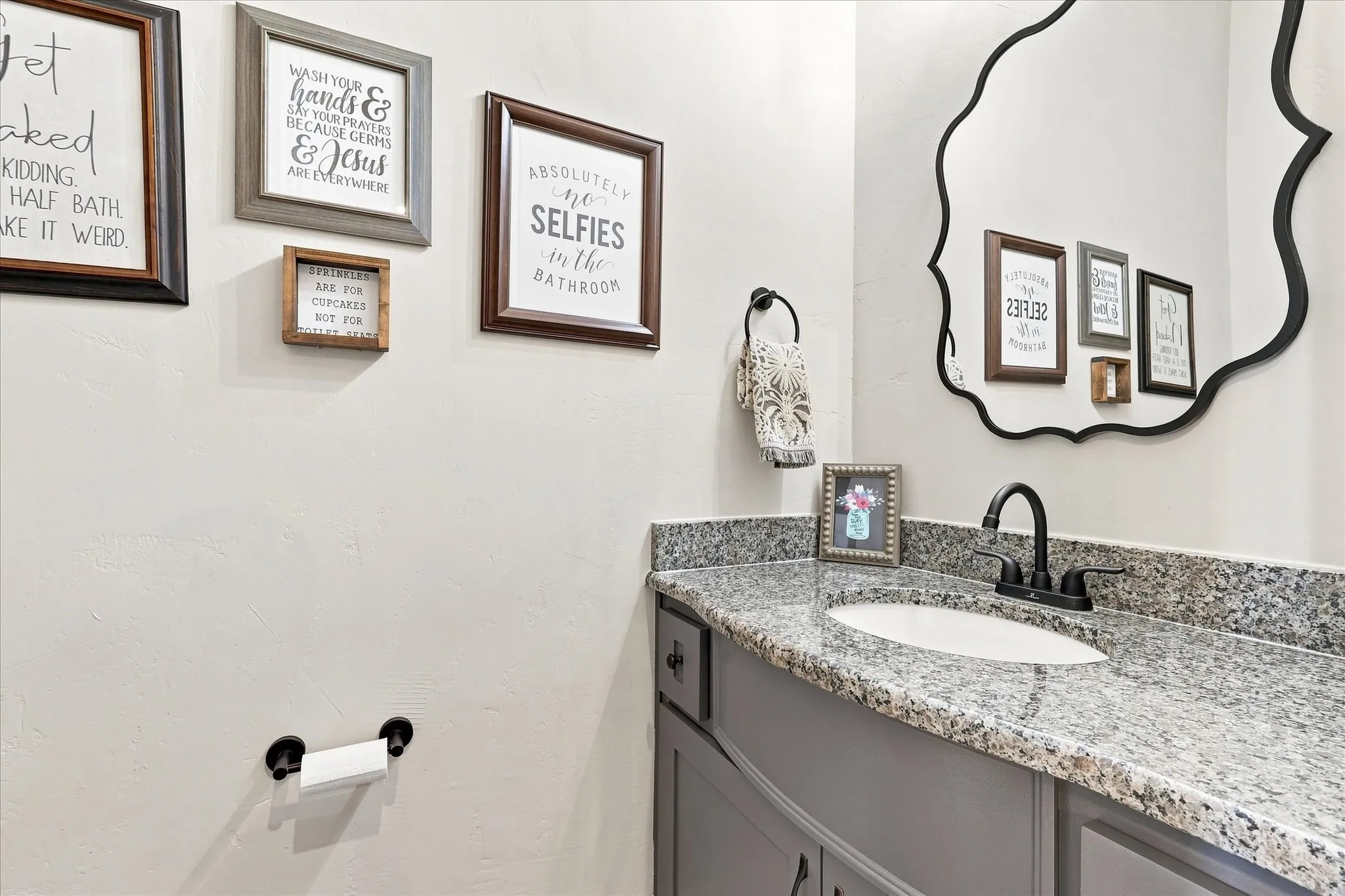 Powder bathroom vanity with a granite countertop, integrated oval sink, and a matte black faucet