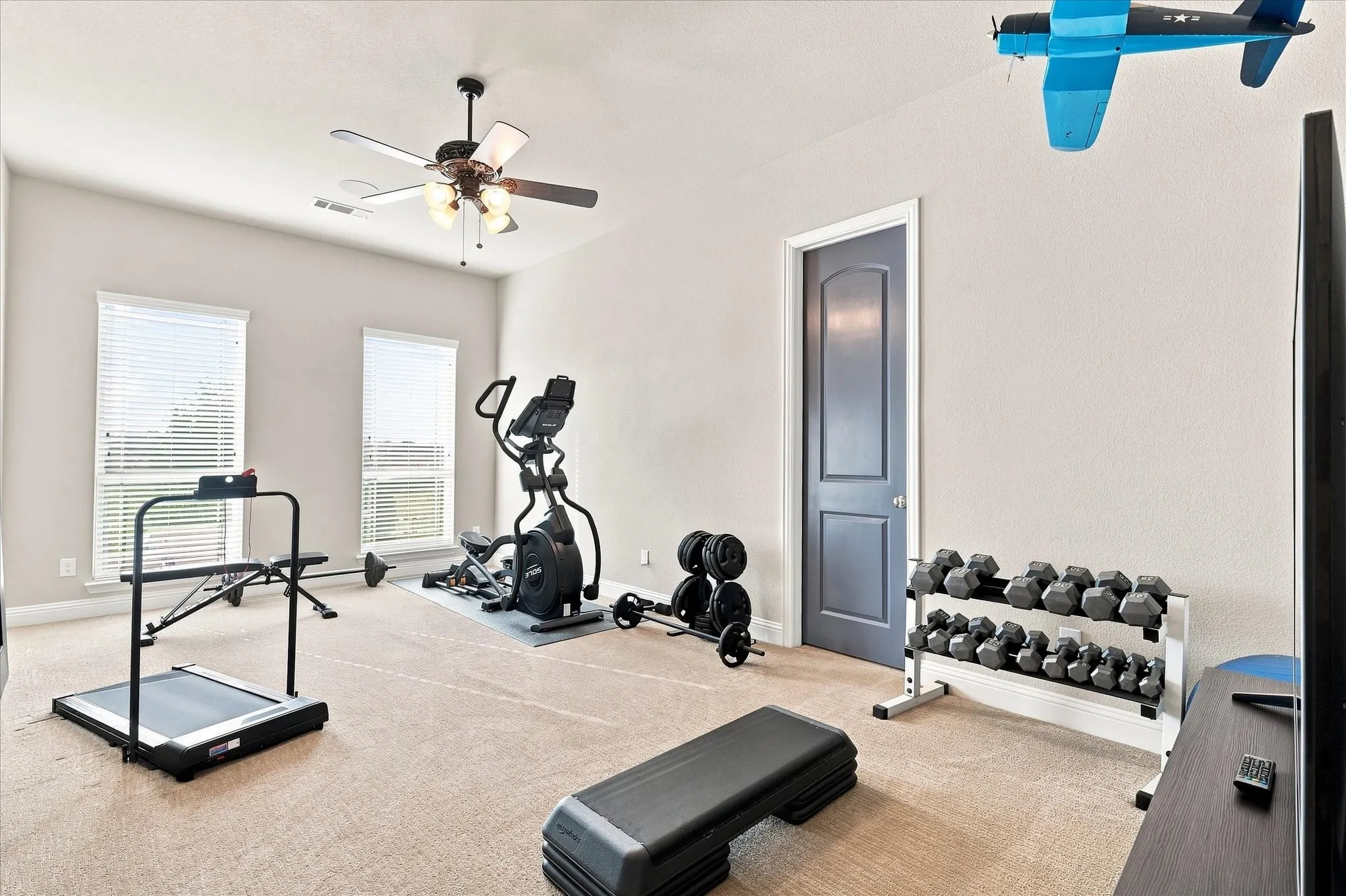 Recessed lighting, two large windows with blinds, ceiling fan with integrated lighting, paneled interior door, and carpeted flooring