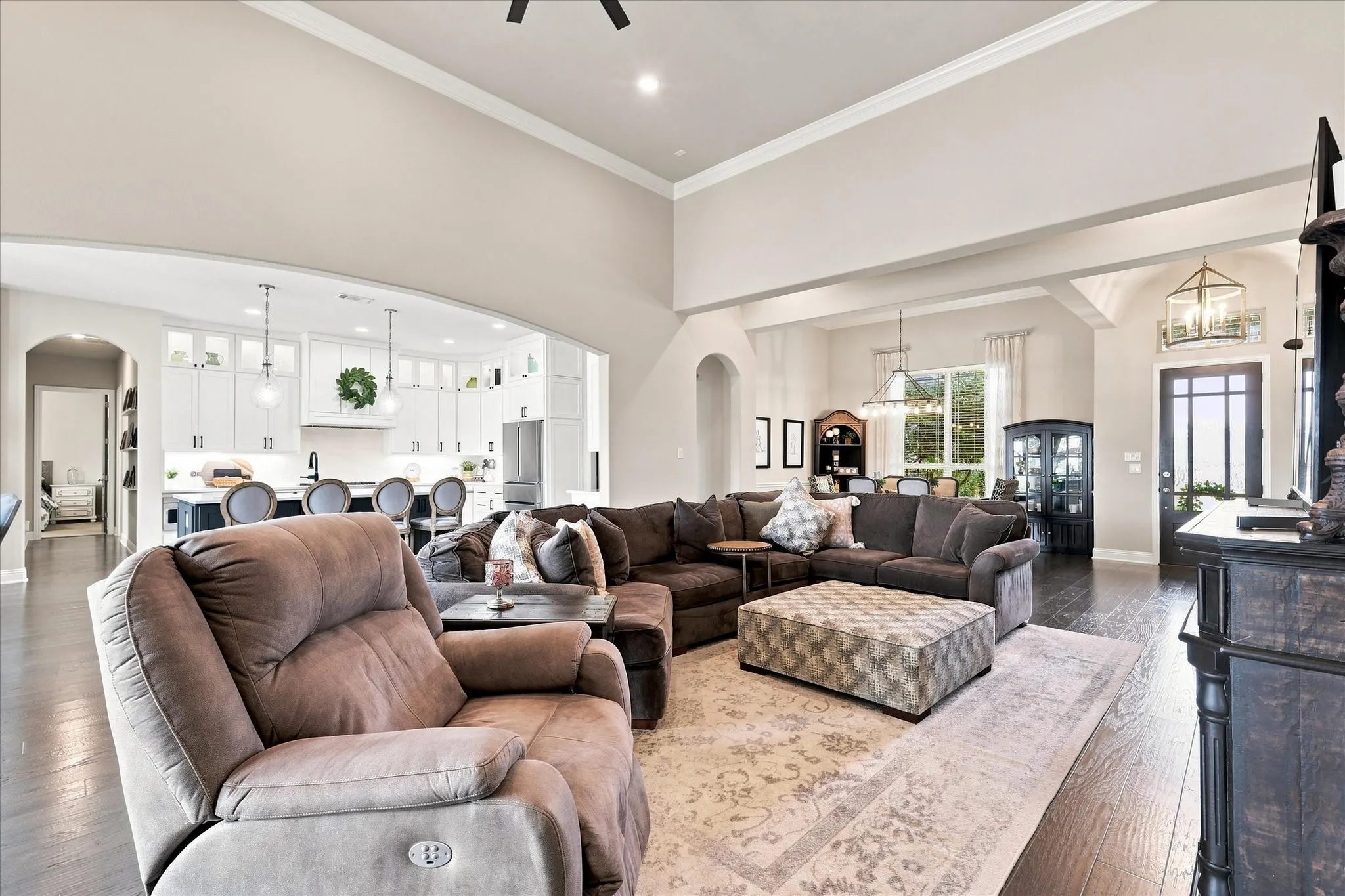 Voluminous living area with high ceilings, dark wood-finish flooring, and recessed lighting