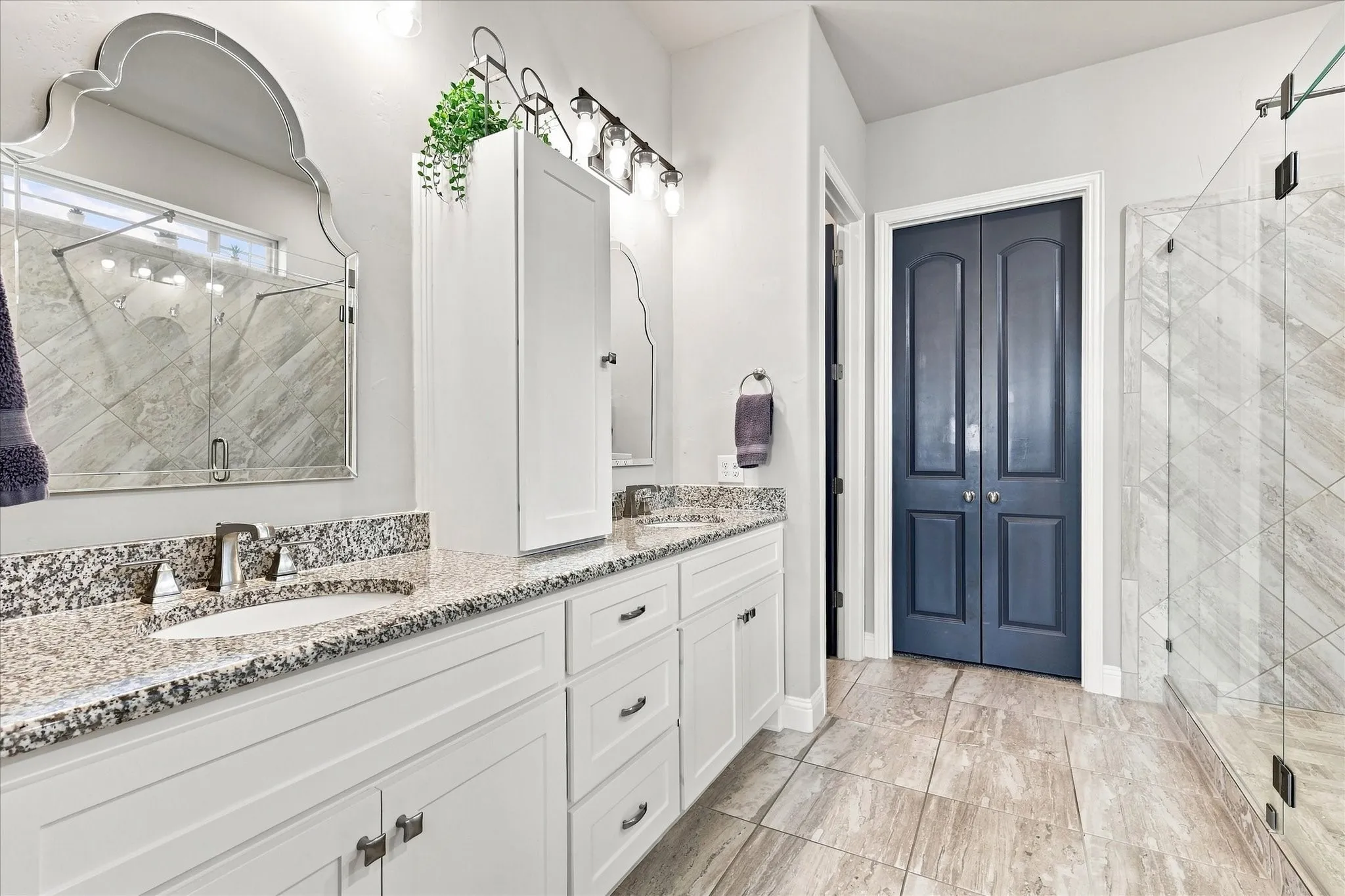 Dual vanity with granite countertops, white cabinetry, and undermount sinks