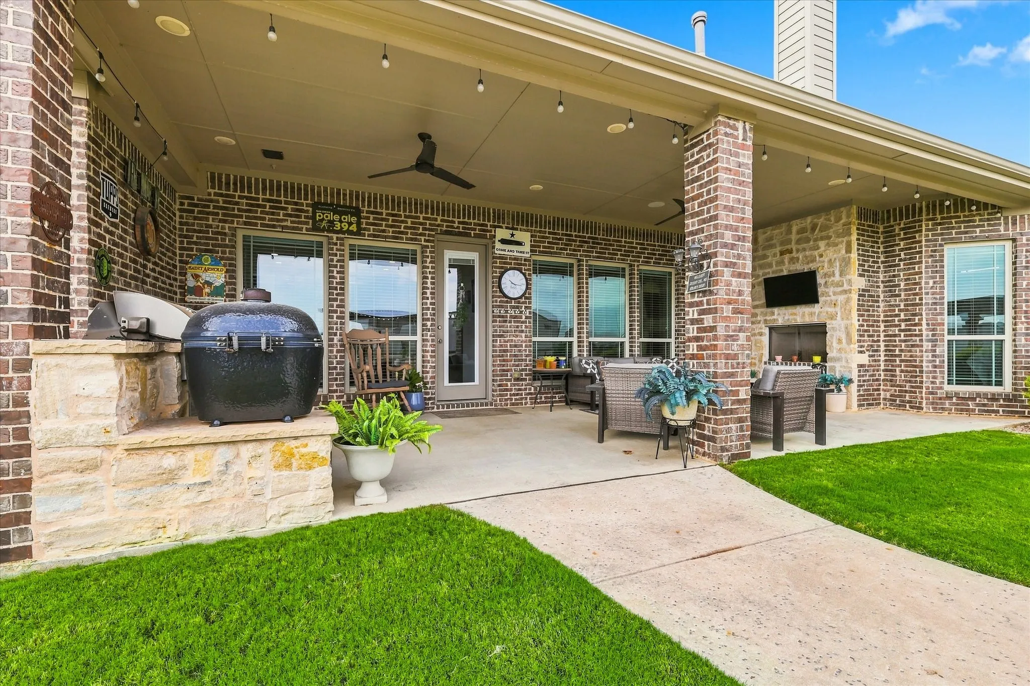 Covered patio with a built-in outdoor kitchen, recessed lighting, ceiling fan, and stone fireplace