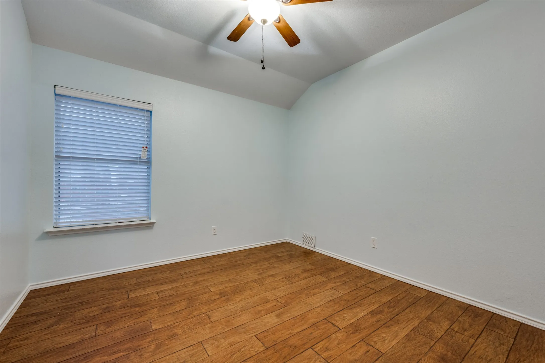 Vaulted ceiling with a ceiling fan, wood-finish flooring, and window blinds