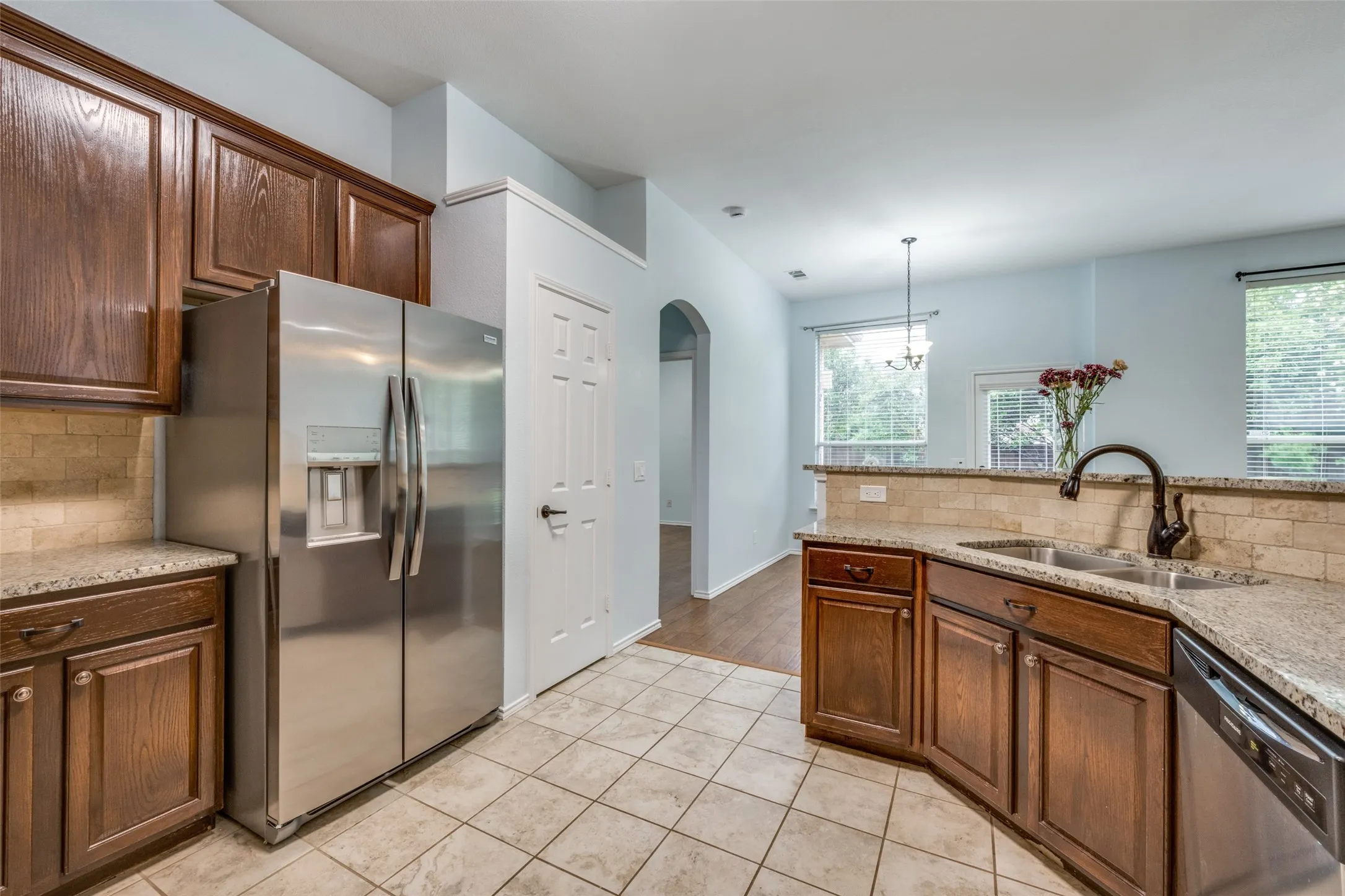 Kitchen featuring wood cabinetry, stone countertops, stainless steel appliances, and tile flooring