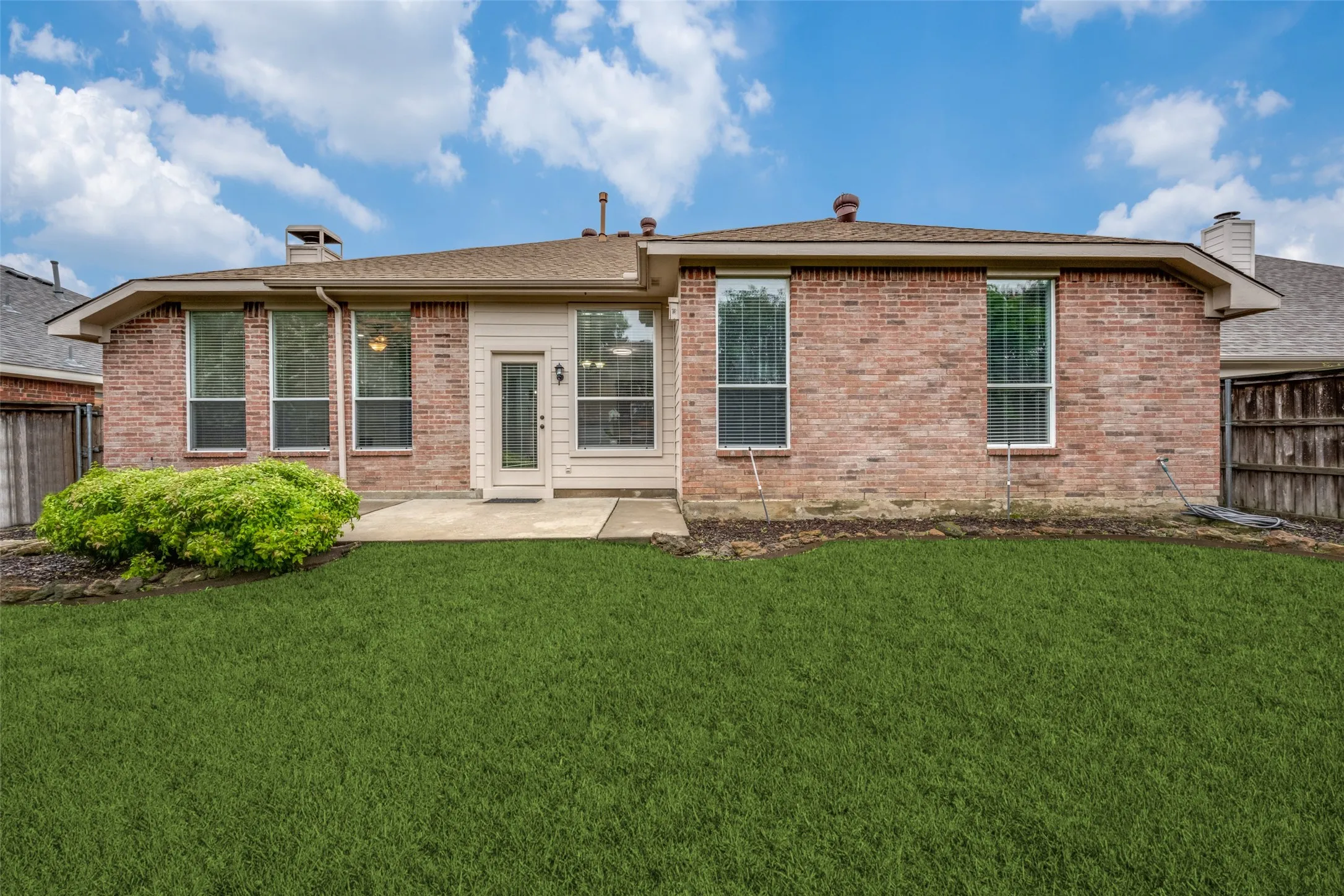 Brick exterior with a shingle roof and multiple windows