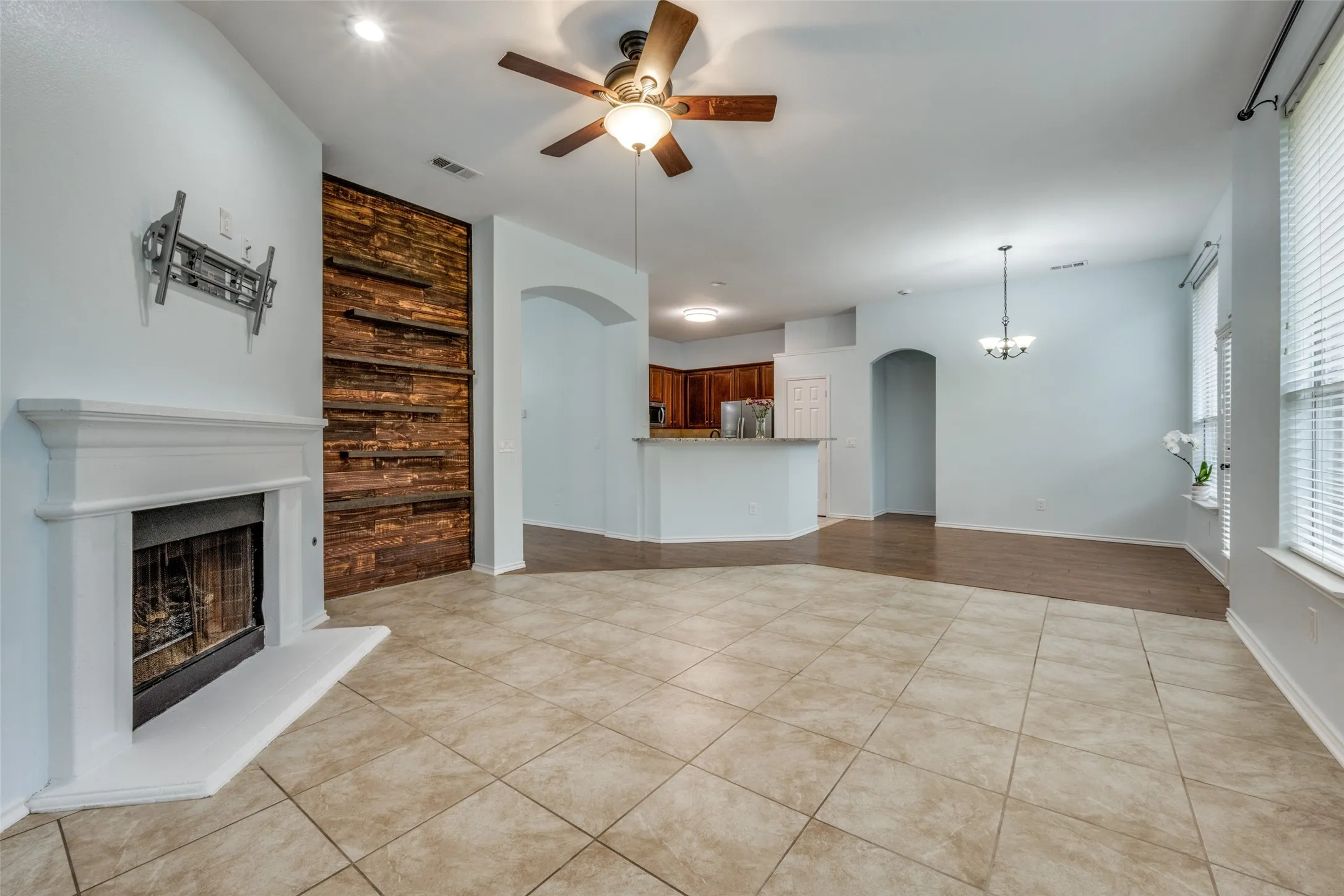 Open-concept living area with tile flooring and a fireplace featuring a white mantel