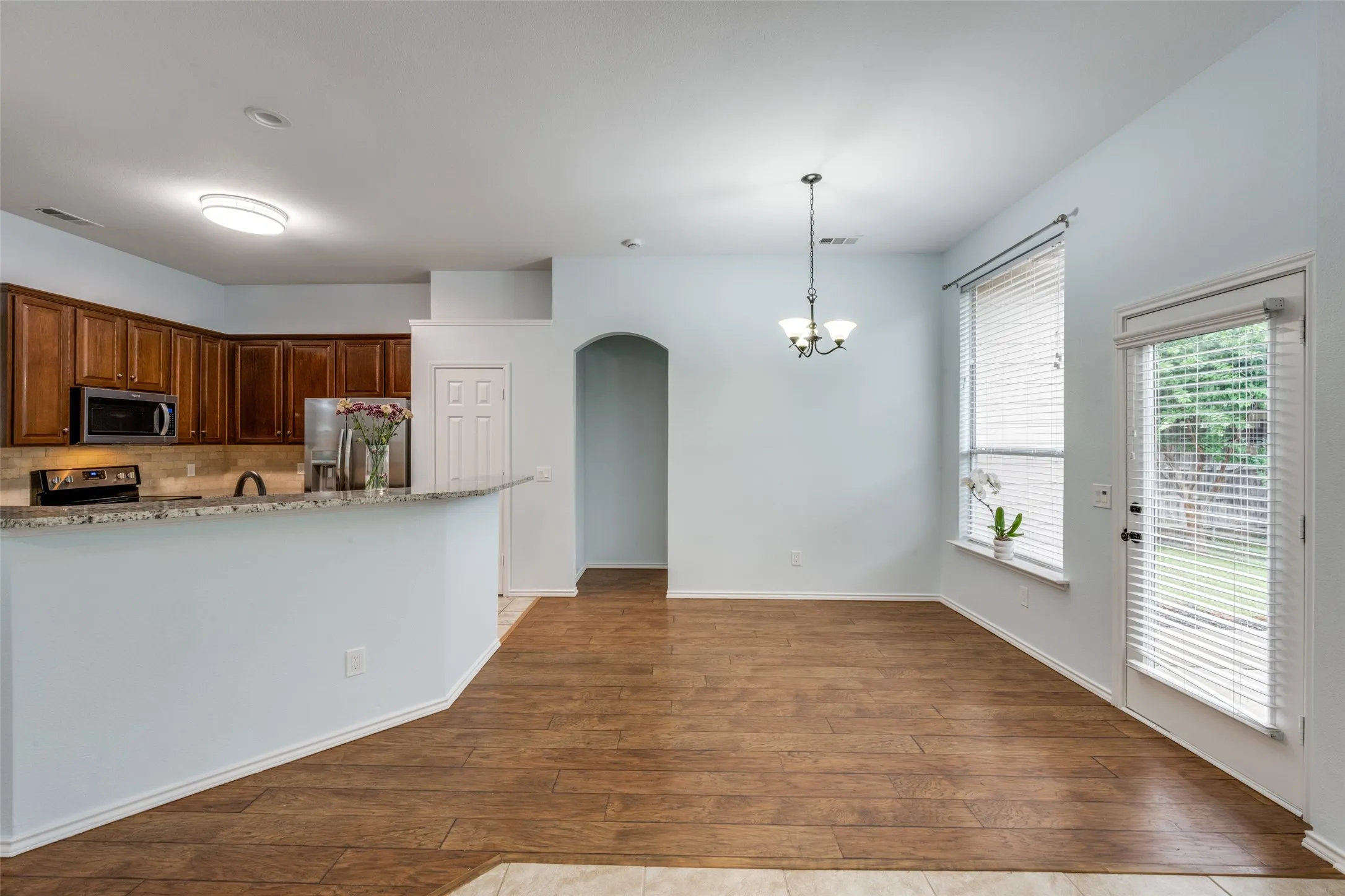 Kitchen area featuring wood-finish cabinetry, stainless steel appliances, and a granite-look countertop