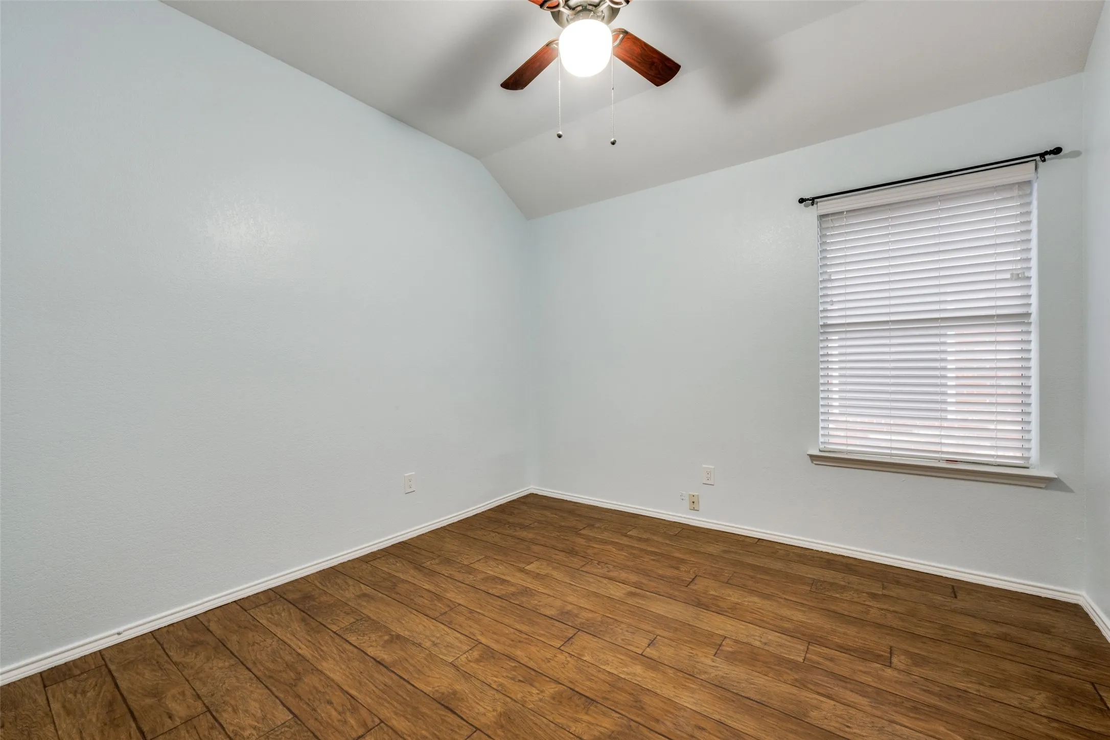Wood-finish flooring with light-toned walls and a window with blinds