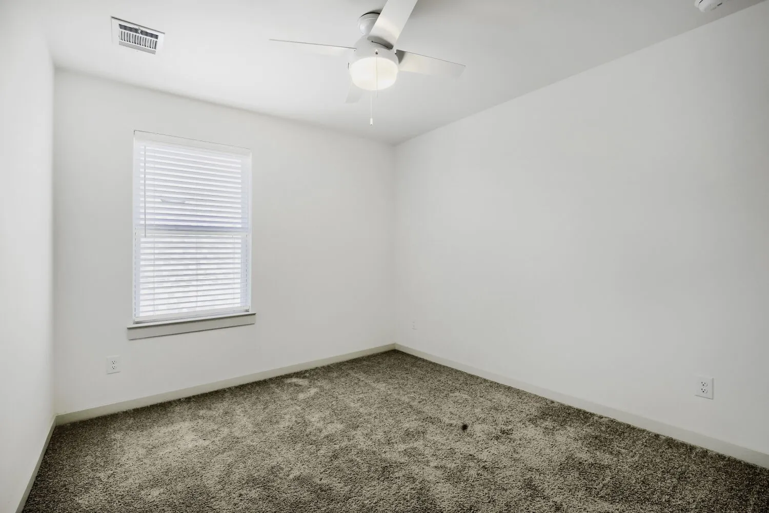Neutral wall color, carpeted flooring, window with blinds, and a ceiling fan
