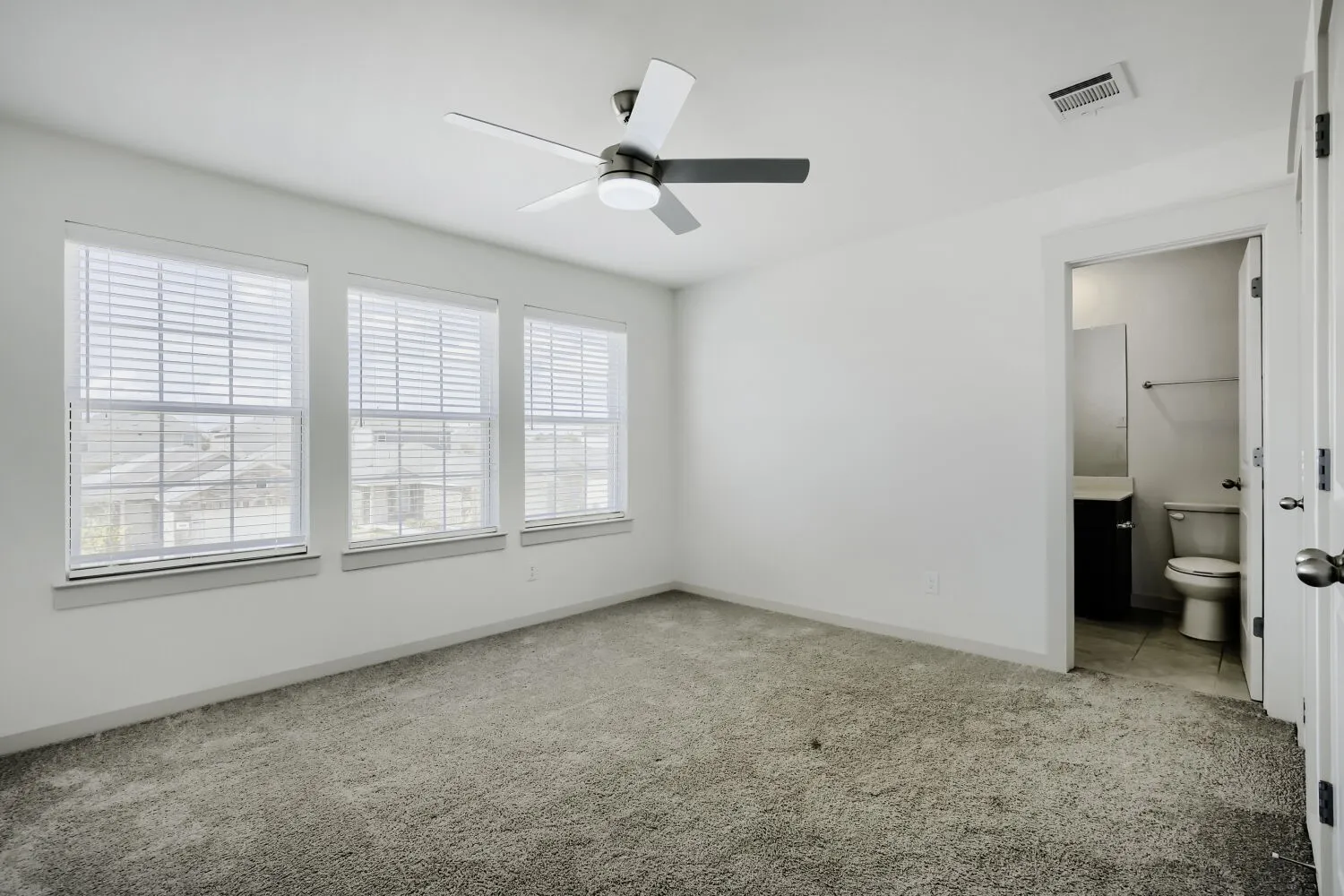 Bright room with three windows featuring blinds, a ceiling fan with integrated lighting, and carpeted flooring