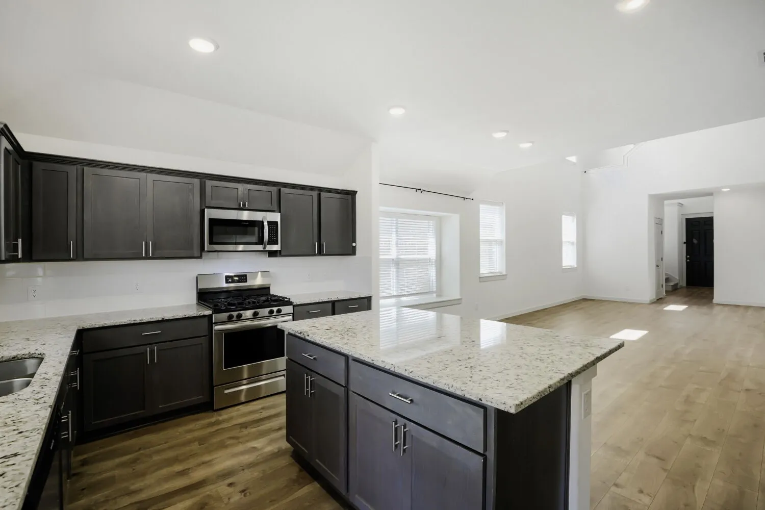 Kitchen featuring stainless steel appliances, dark wood-finish cabinetry, and light-toned countertops