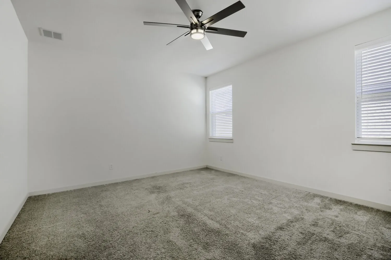 Carpeted room featuring multiple windows with blinds and a ceiling​​‌​​​​‌​​‌‌​‌‌​​​‌‌​‌​‌​‌​​​‌​​ fan