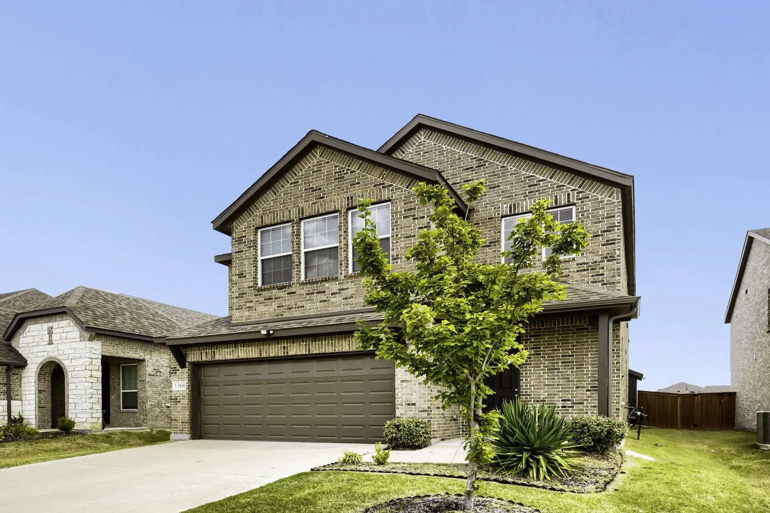 Brick exterior with stone accents, two-car garage, and mature landscaping