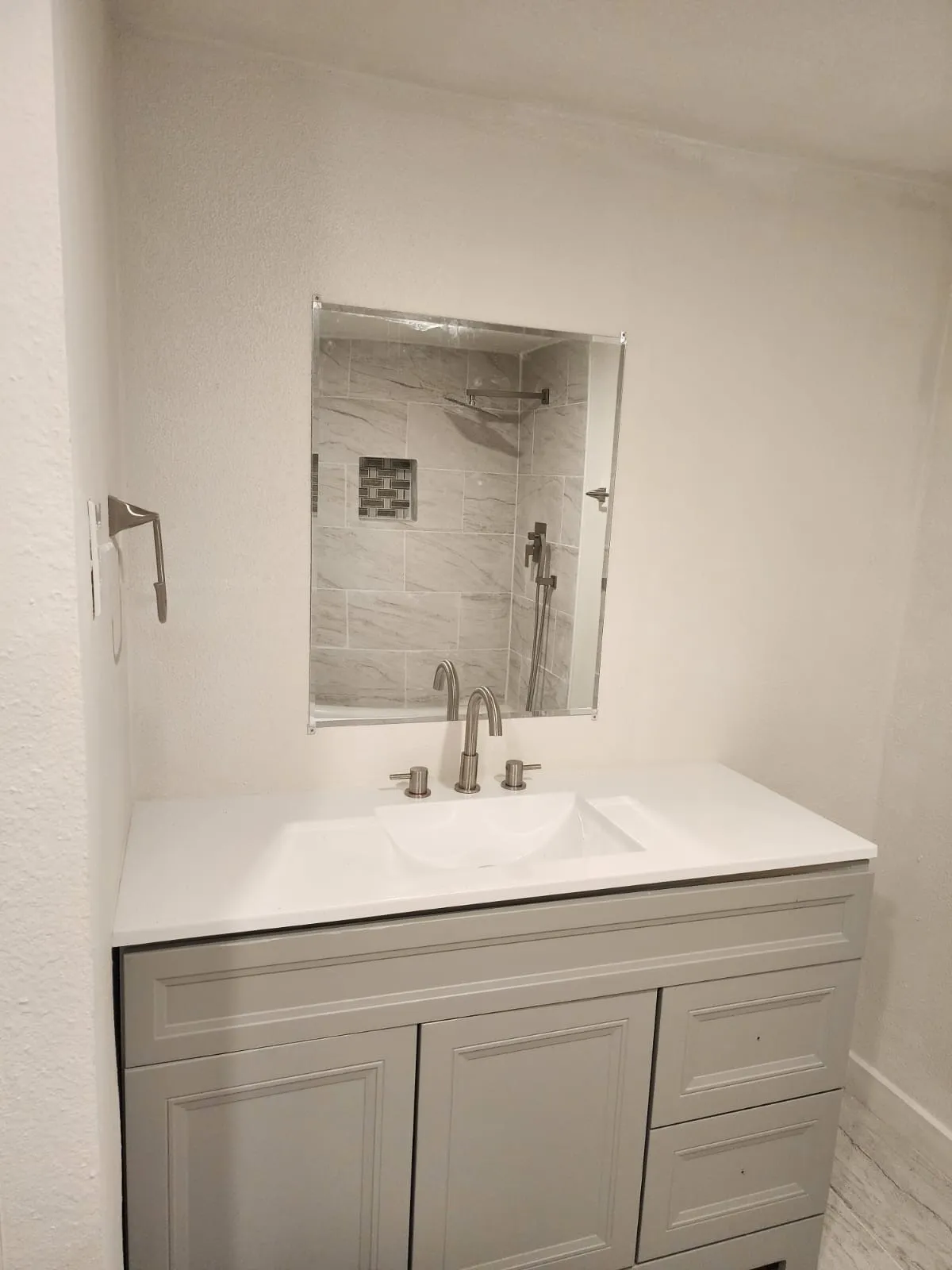 Vanity with an integrated white sink, brushed nickel faucet, and a large mirror