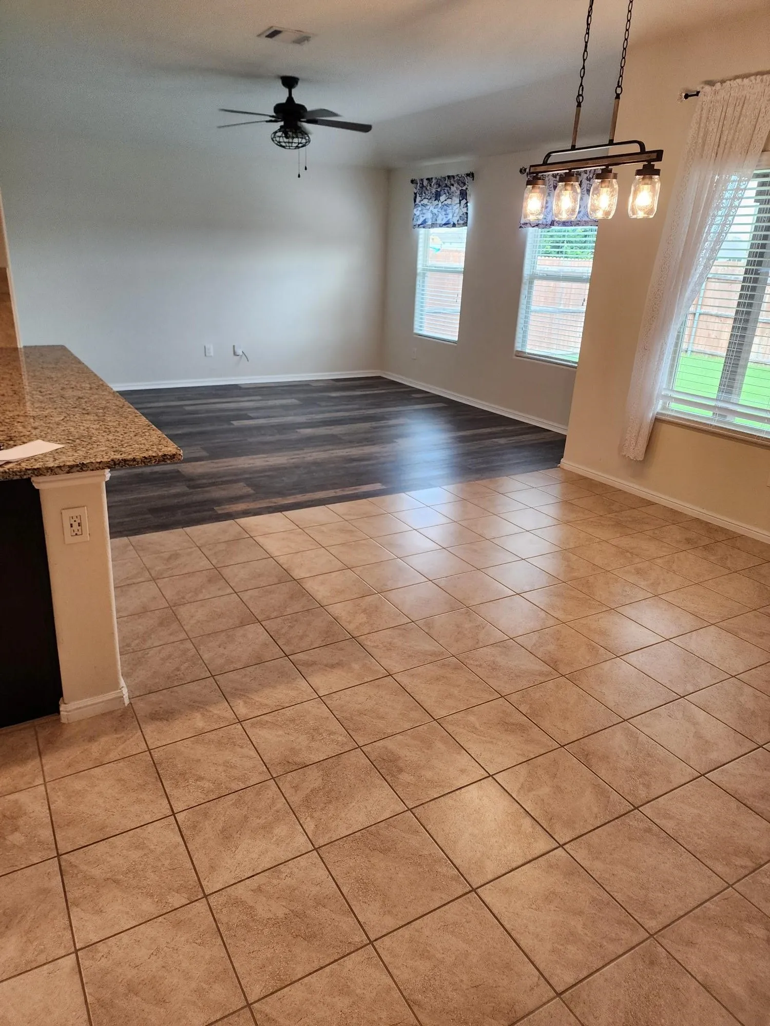 Empty room featuring a healthy amount of sunlight, light hardwood / wood-style floors, and ceiling fan with notable chandelier