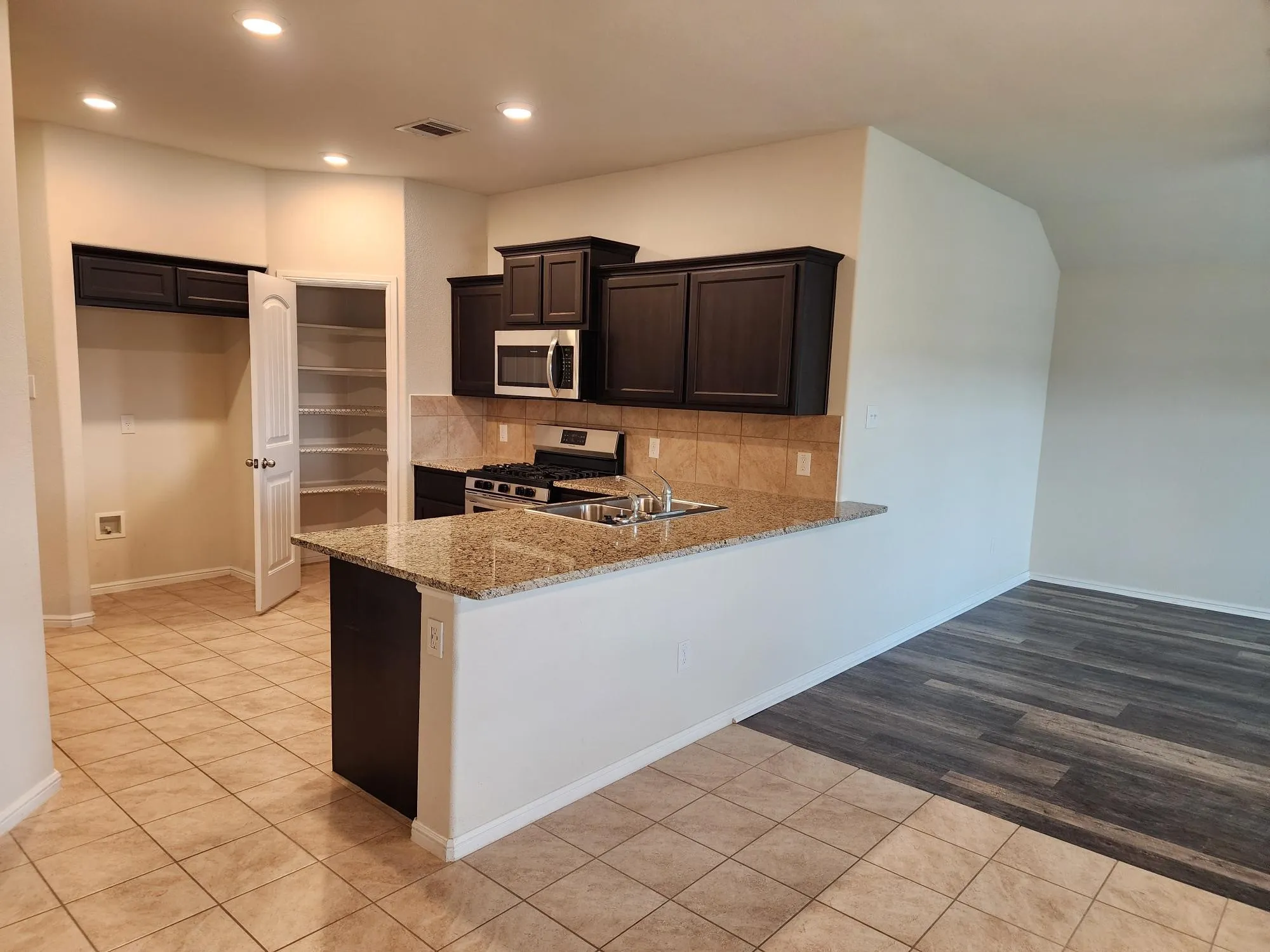 Kitchen with kitchen peninsula, tasteful backsplash, stainless steel appliances, light stone counters, and light tile floors