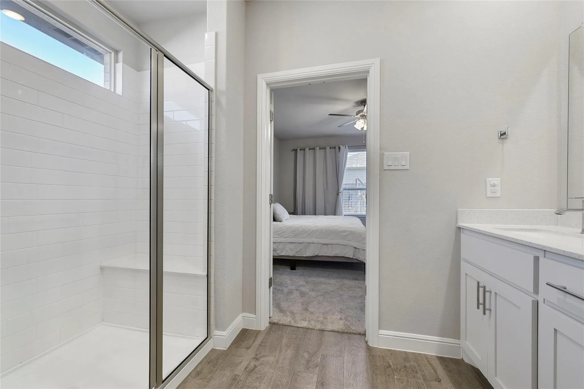 Bathroom featuring ceiling fan, hardwood / wood-style flooring, a shower with door, and vanity