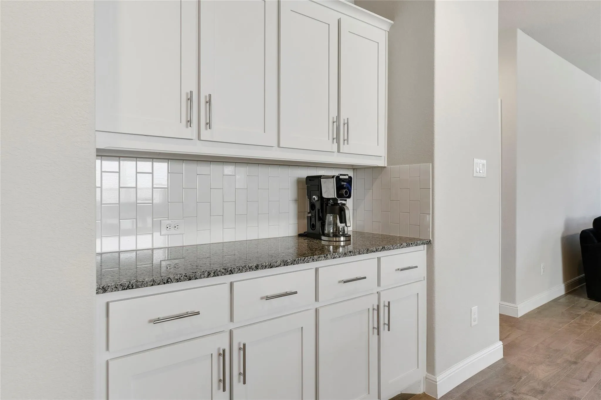 Kitchen featuring white cabinets, light hardwood / wood-style floors, backsplash, and dark stone countertops