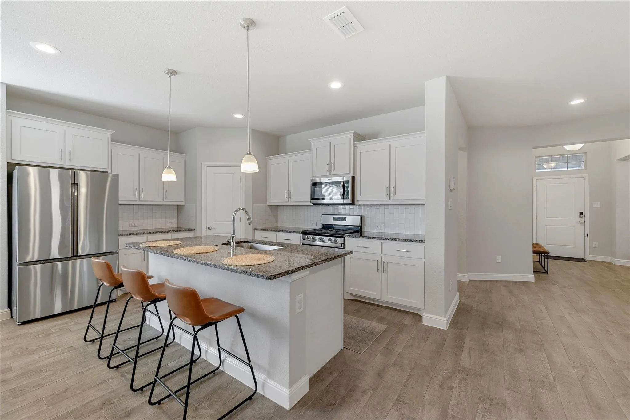 Kitchen featuring light hardwood / wood-style floors, stainless steel appliances, sink, white cabinetry, and dark stone countertops