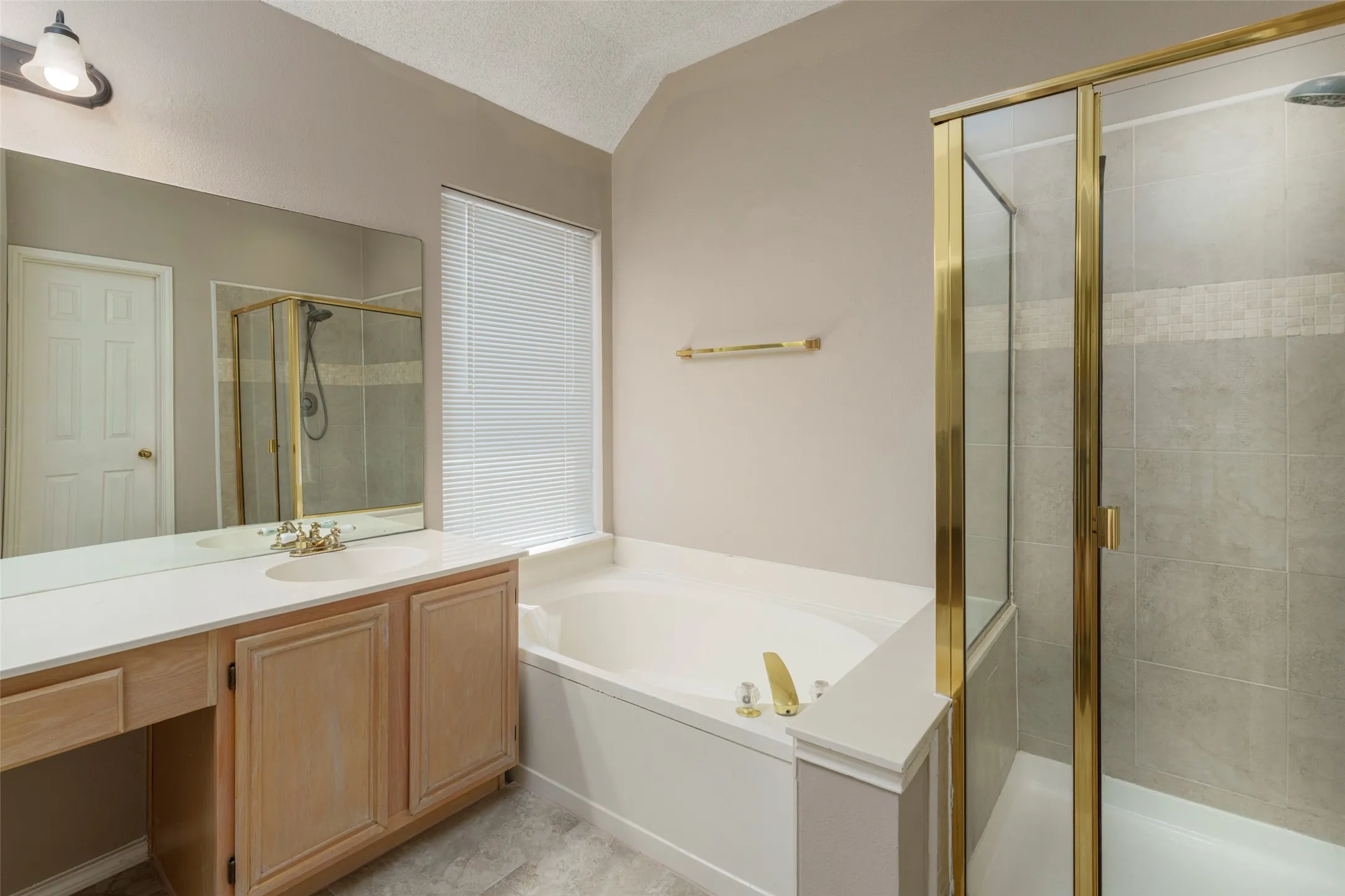 Vanity with integrated sink, built-in bathtub, and enclosed shower with tile surround