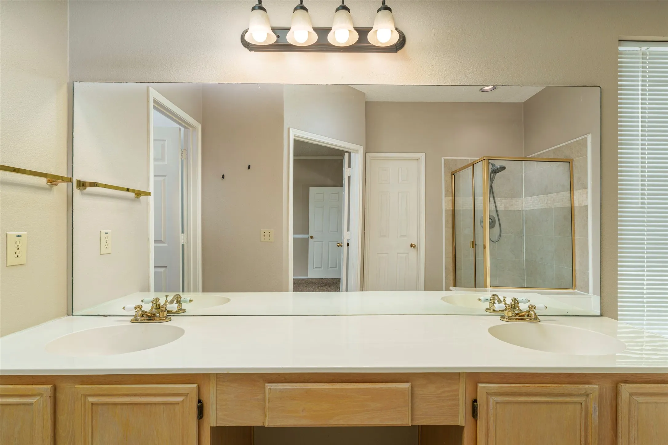 Dual sink vanity with light wood-finish cabinetry and a single light fixture