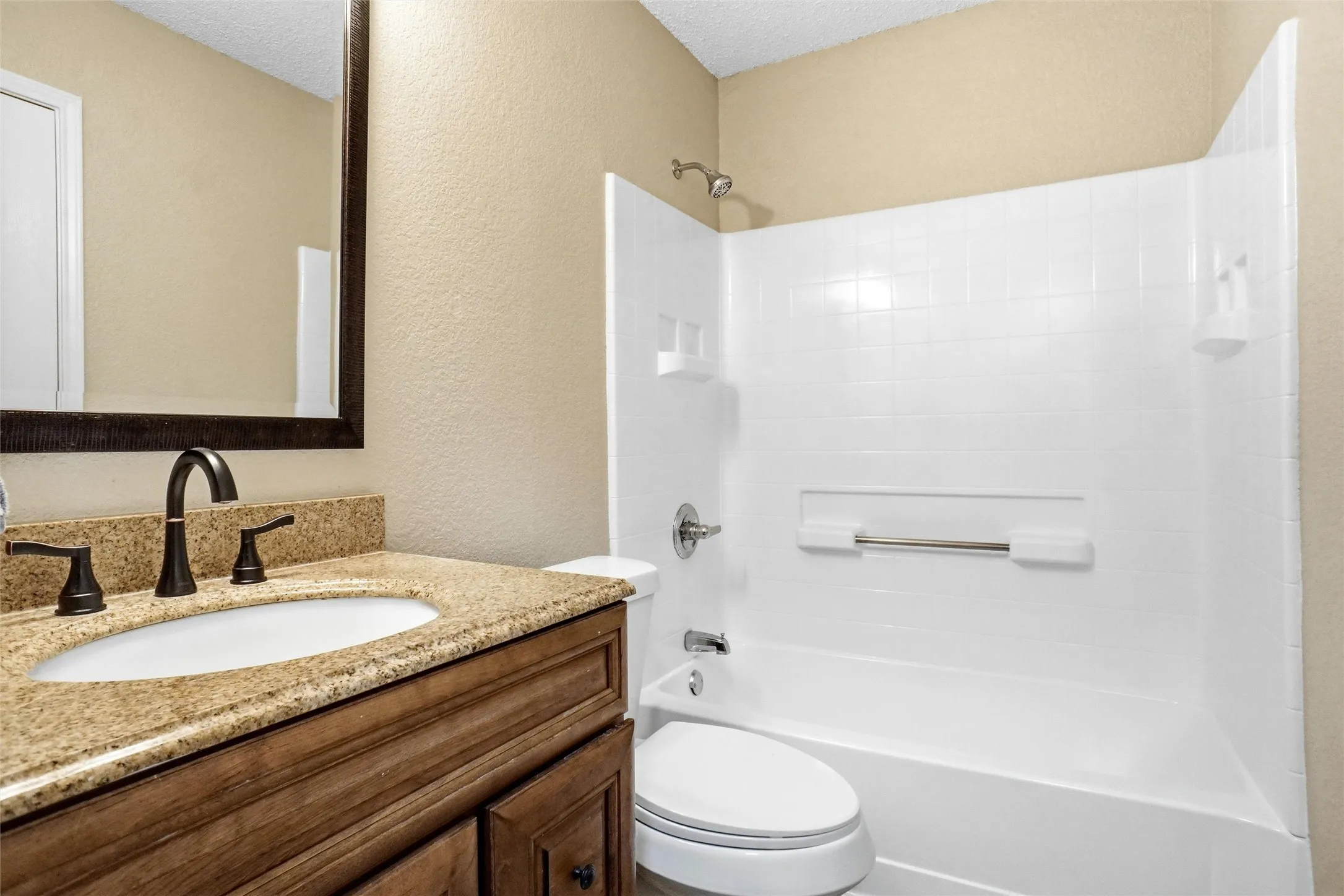 Bathroom featuring a wood-finish vanity with a stone countertop, an undermount sink, and a dark-finish faucet