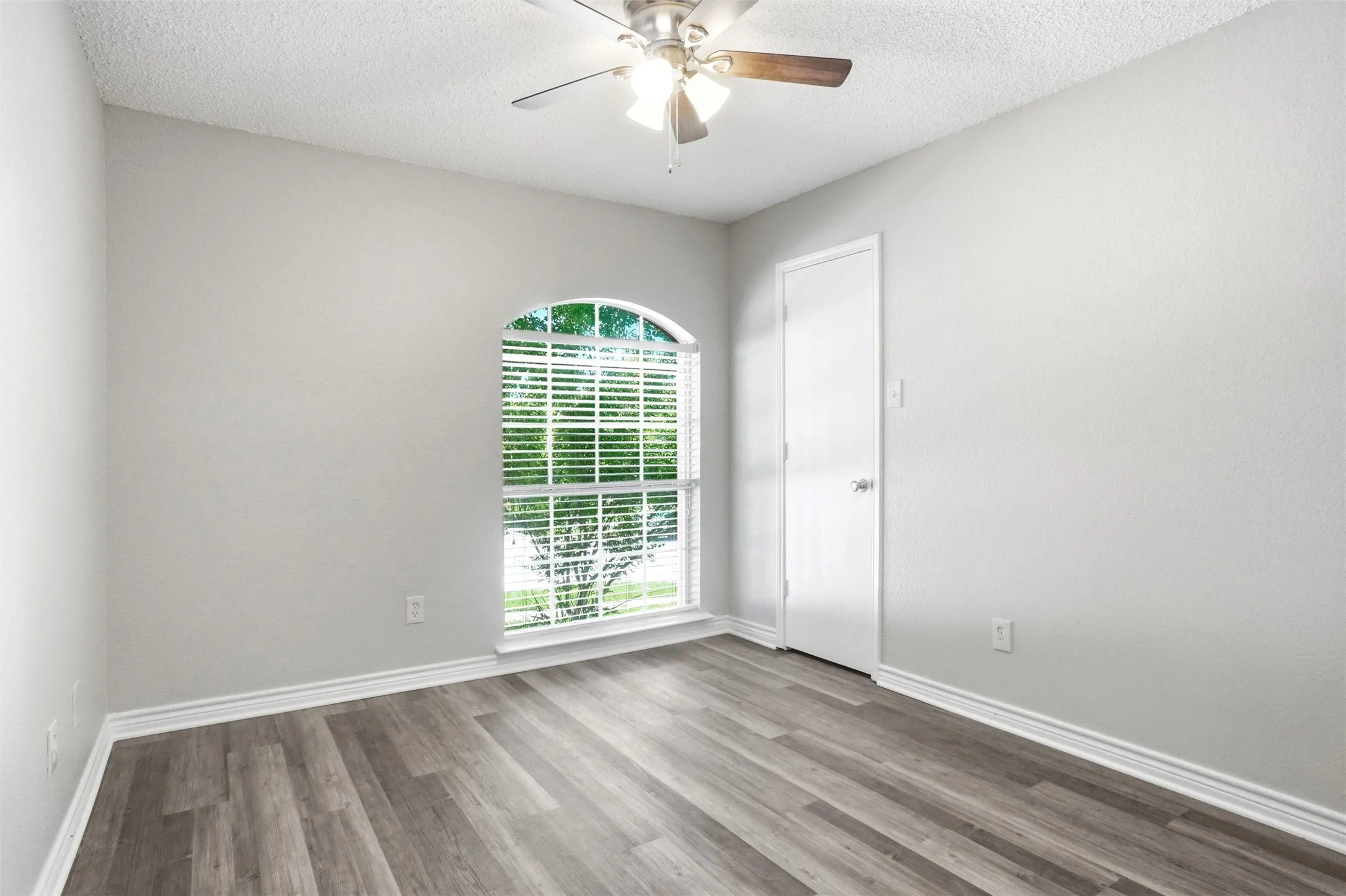 Arched window with blinds,  luxury vinyl plank flooring, ceiling fan