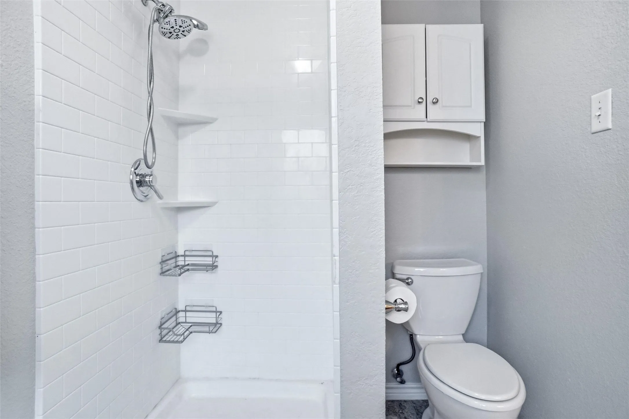 White subway tile shower surround with chrome fixtures and built-in shelving