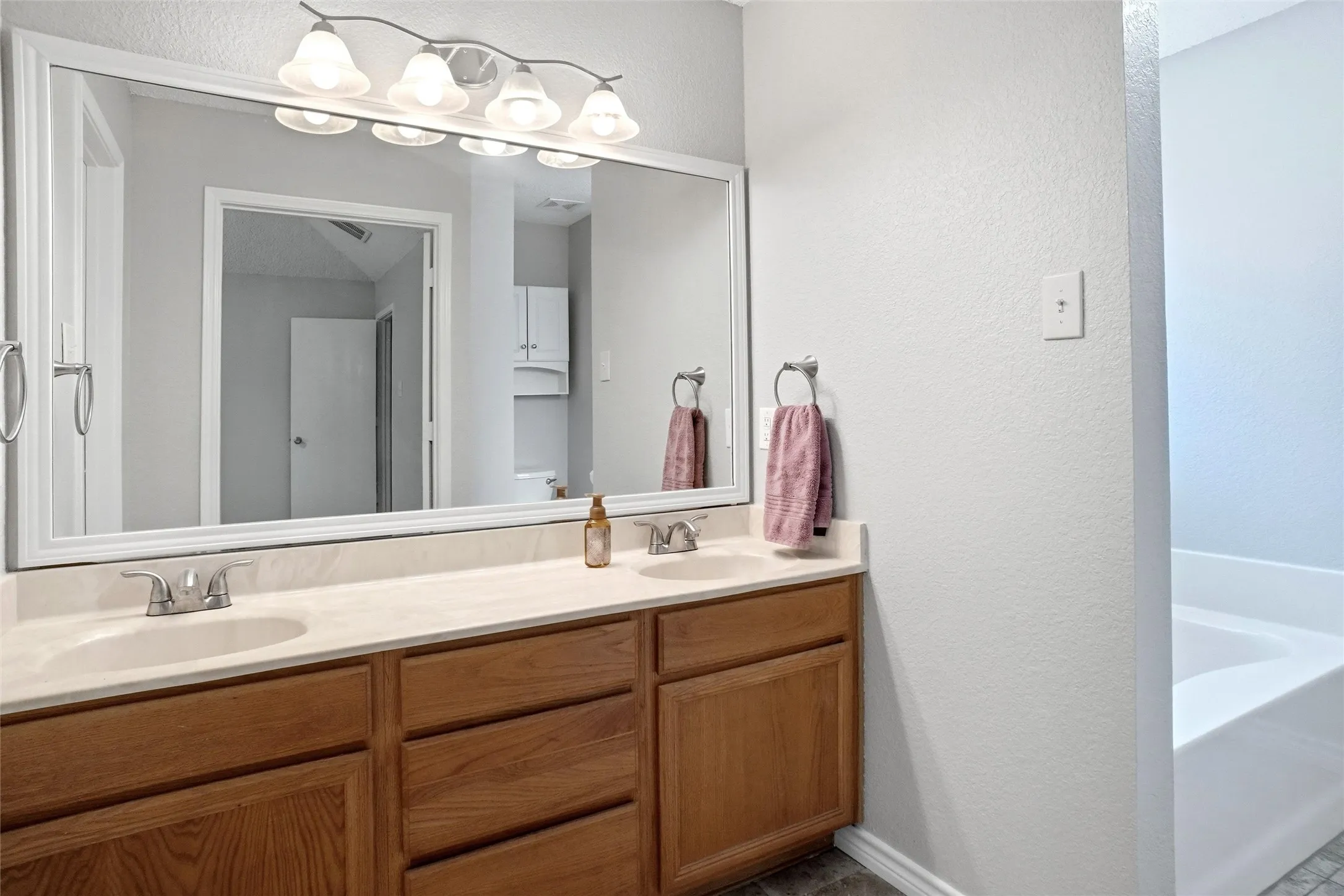 Double vanity with individual undermount sinks, wood-finish cabinetry, and a full-width mirror