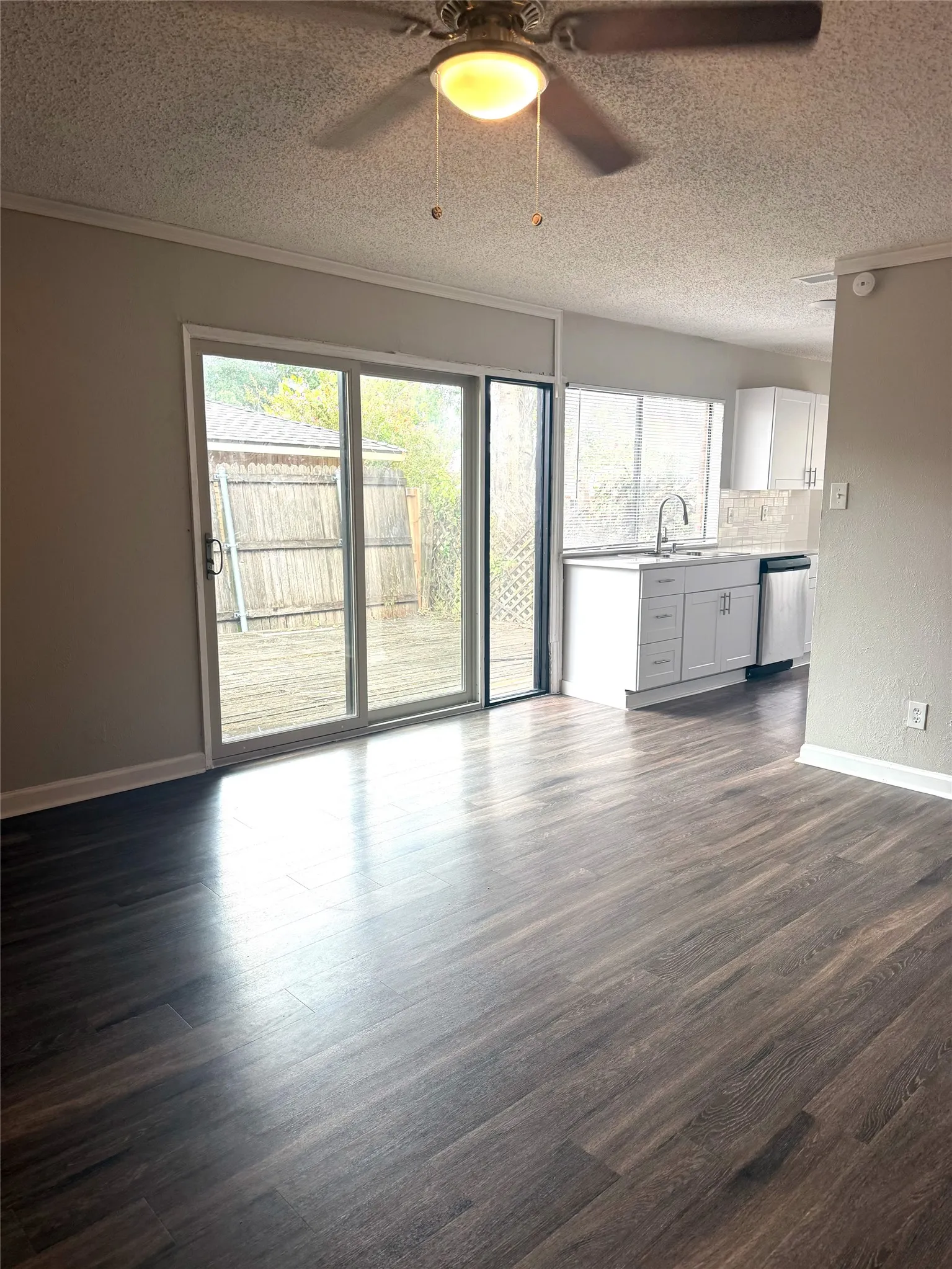 Wood-finish flooring, sliding glass doors, white cabinetry, integrated sink, and stainless steel appliances