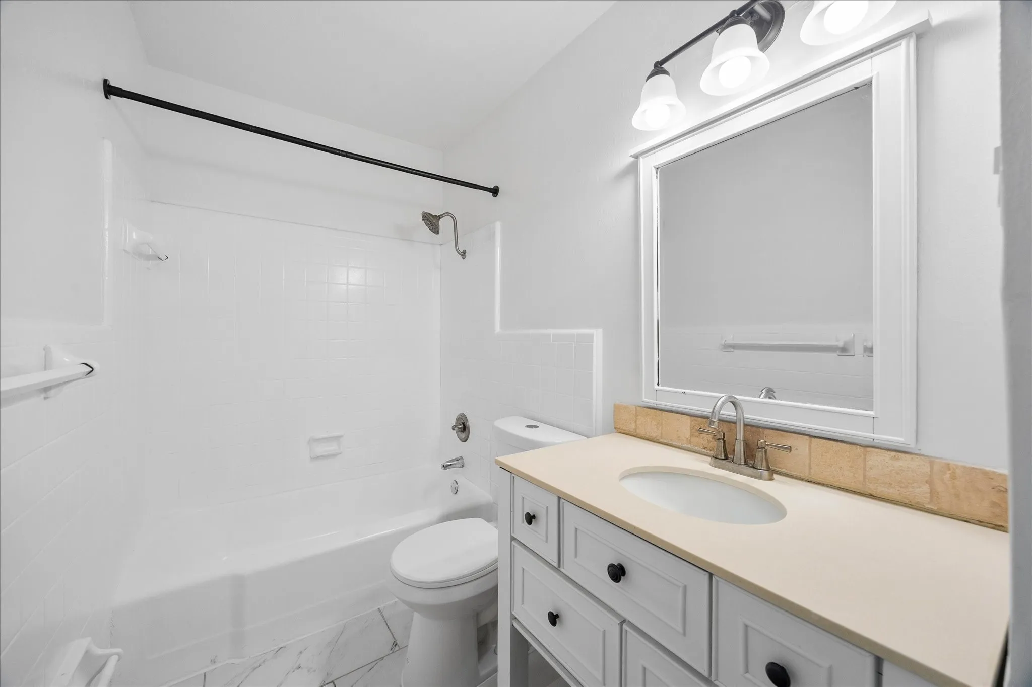 Full bathroom with vanity and tub/shower combination.