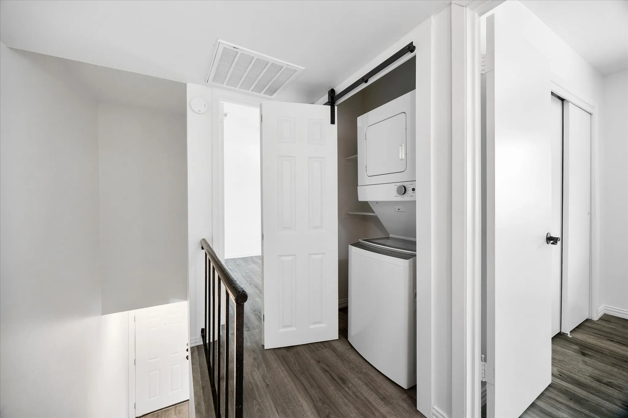 Laundry closet with stacked washer and dryer included.