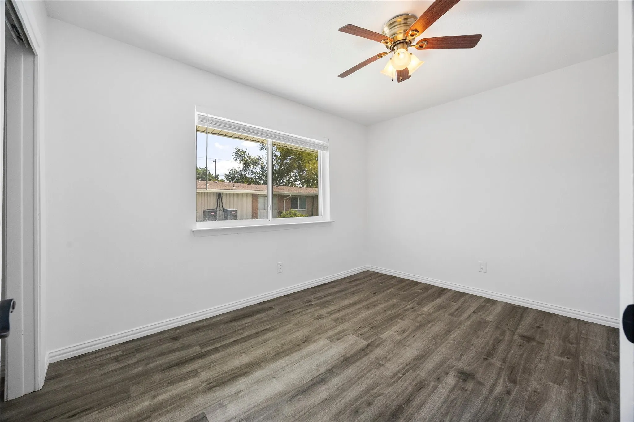 Spacious primary bedroom with large window and ceiling fan.